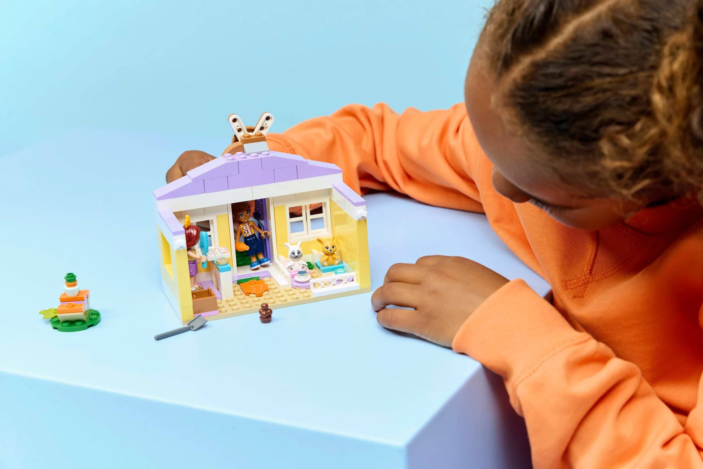 Fetiță se joacă cu setul LEGO Heartlake City Bunny Hotel. Imagine care arată hotelul și personajele.