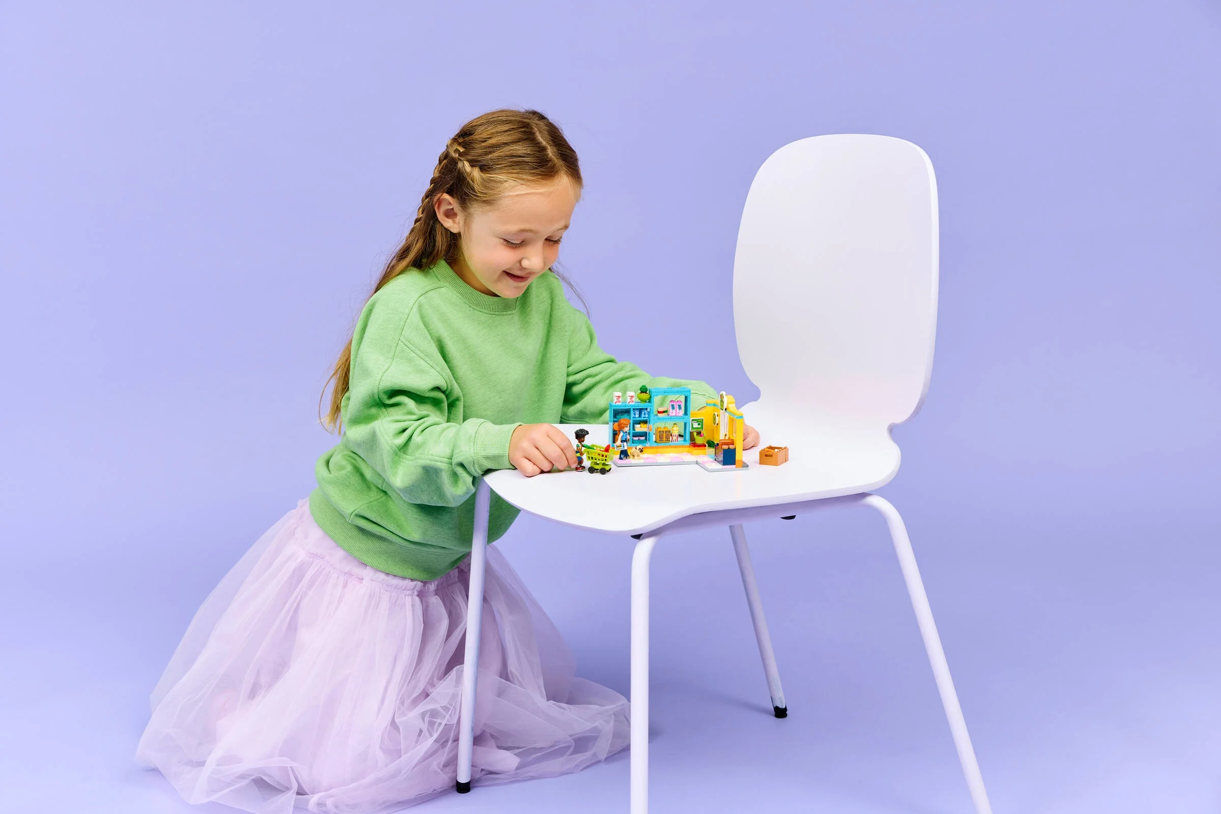 O fată se joacă cu supermarketul LEGO Friends. Zâmbește și împinge căruciorul.