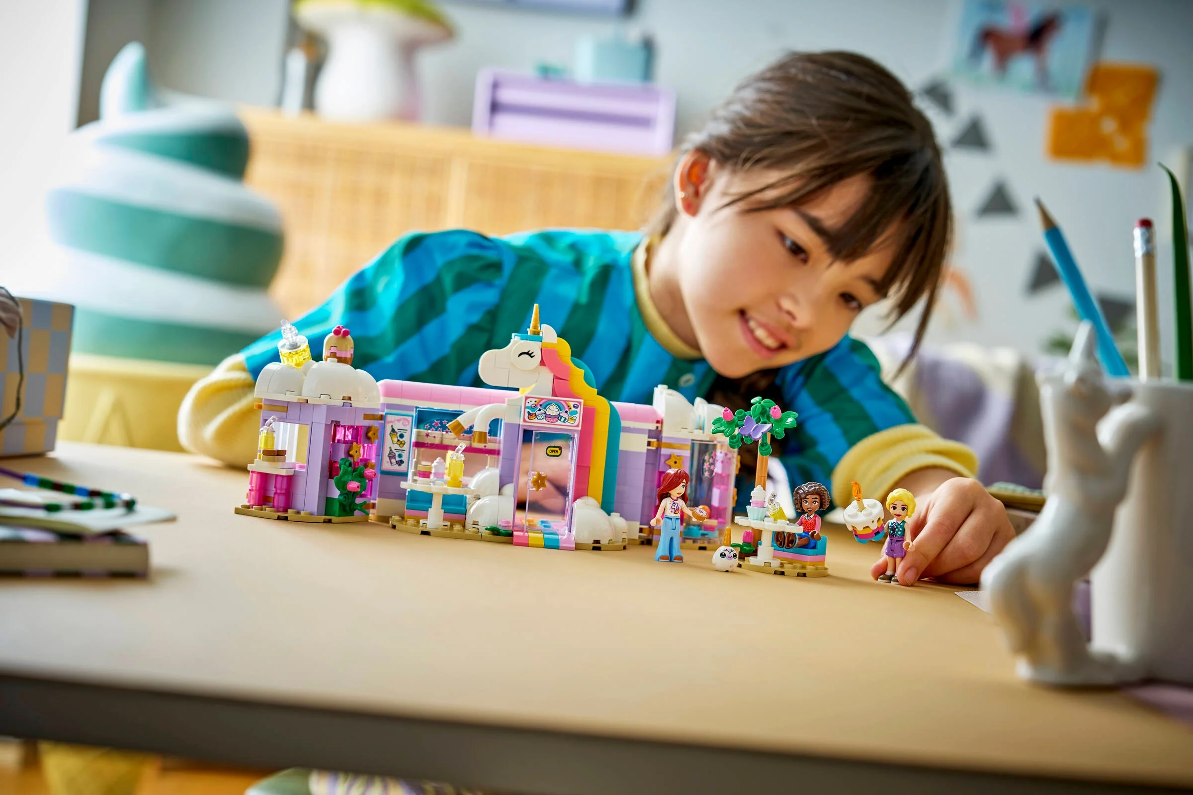 O fetiță se joacă cu setul LEGO Friends Cafeneaua Unicorn Visător. 