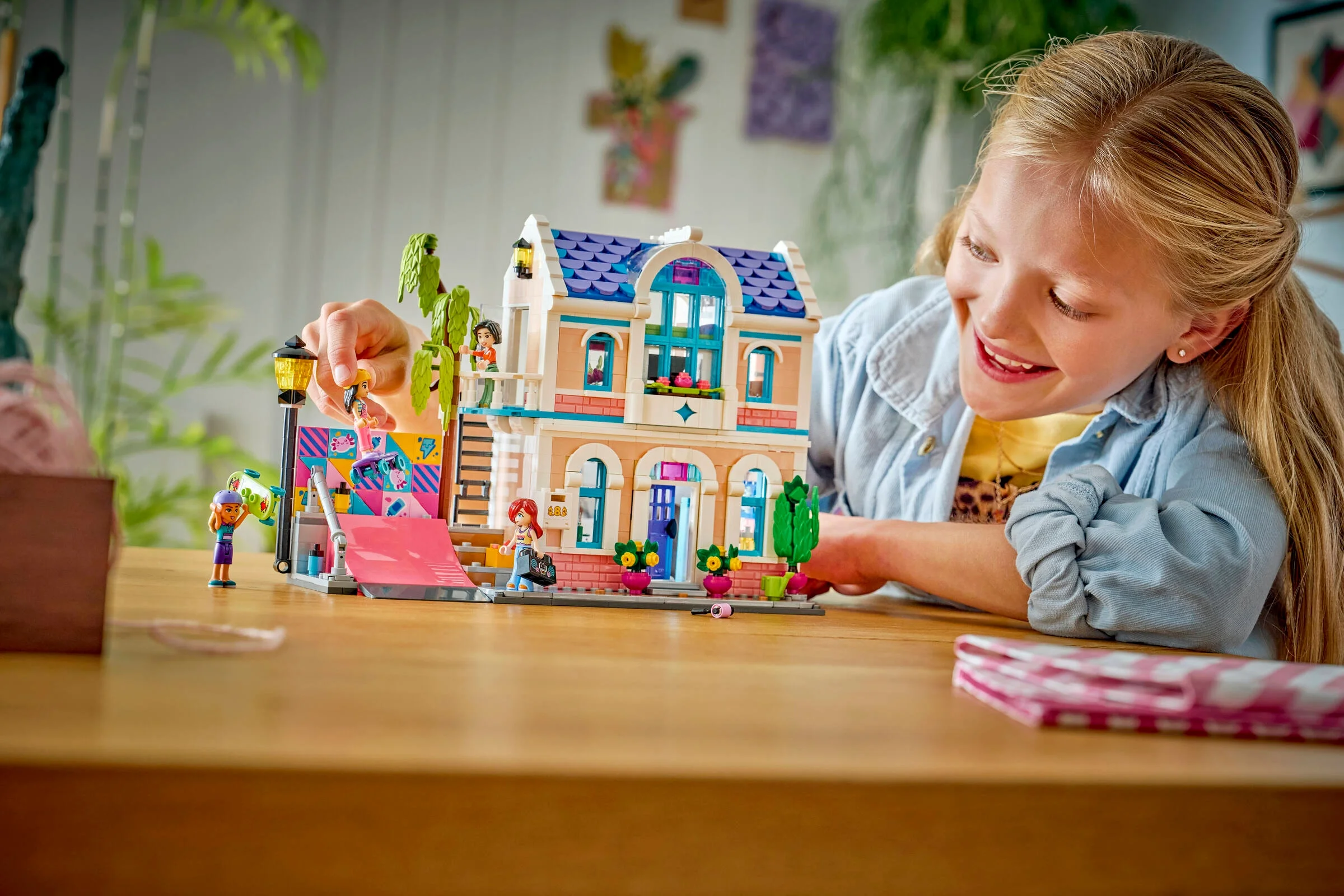 Fată zâmbitoare se joacă cu casa LEGO Friends a Liannei, set 42687.