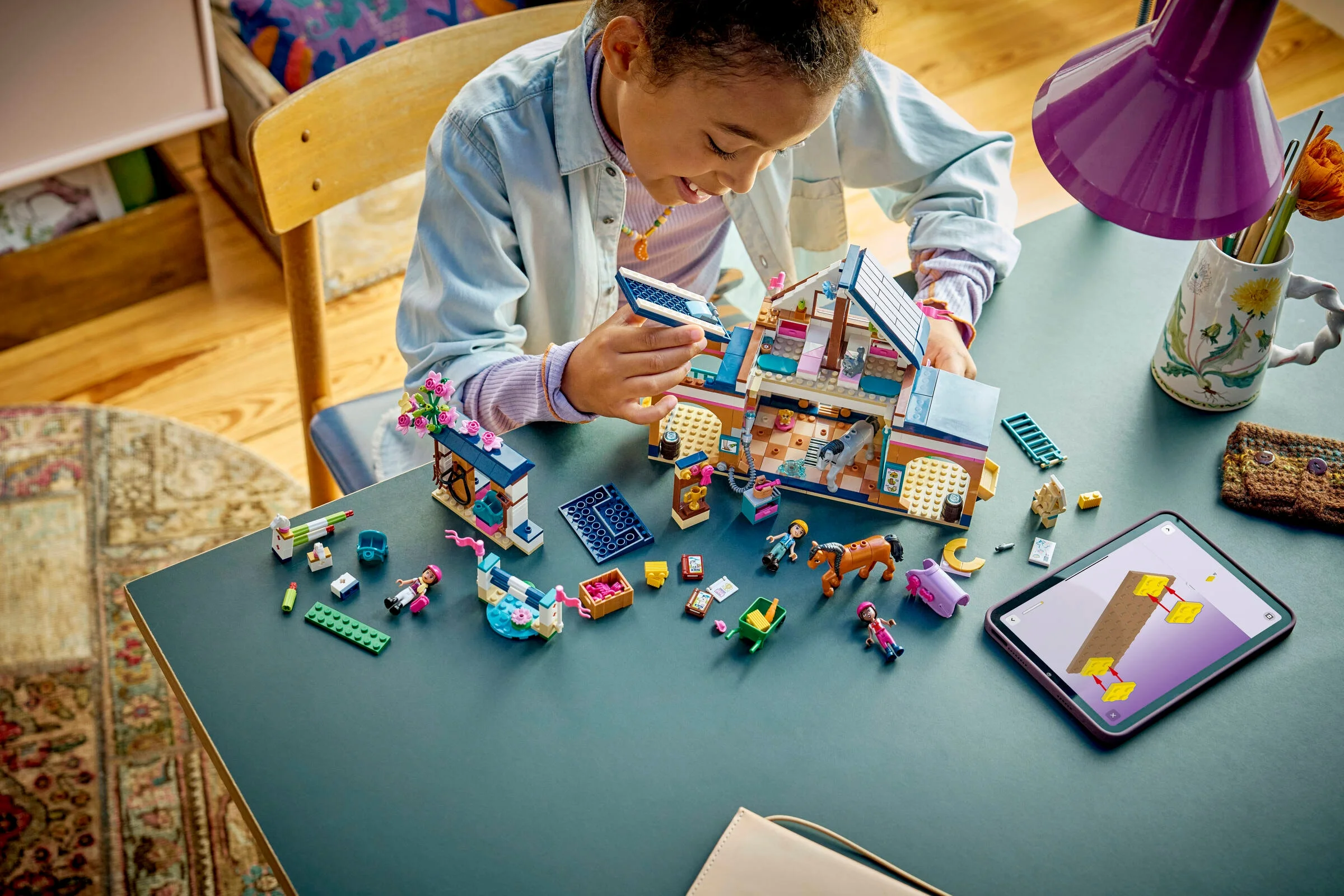 O fetiță construiește setul LEGO 42688 Academie de Echitație. Atmosferă prietenoasă și creativă.