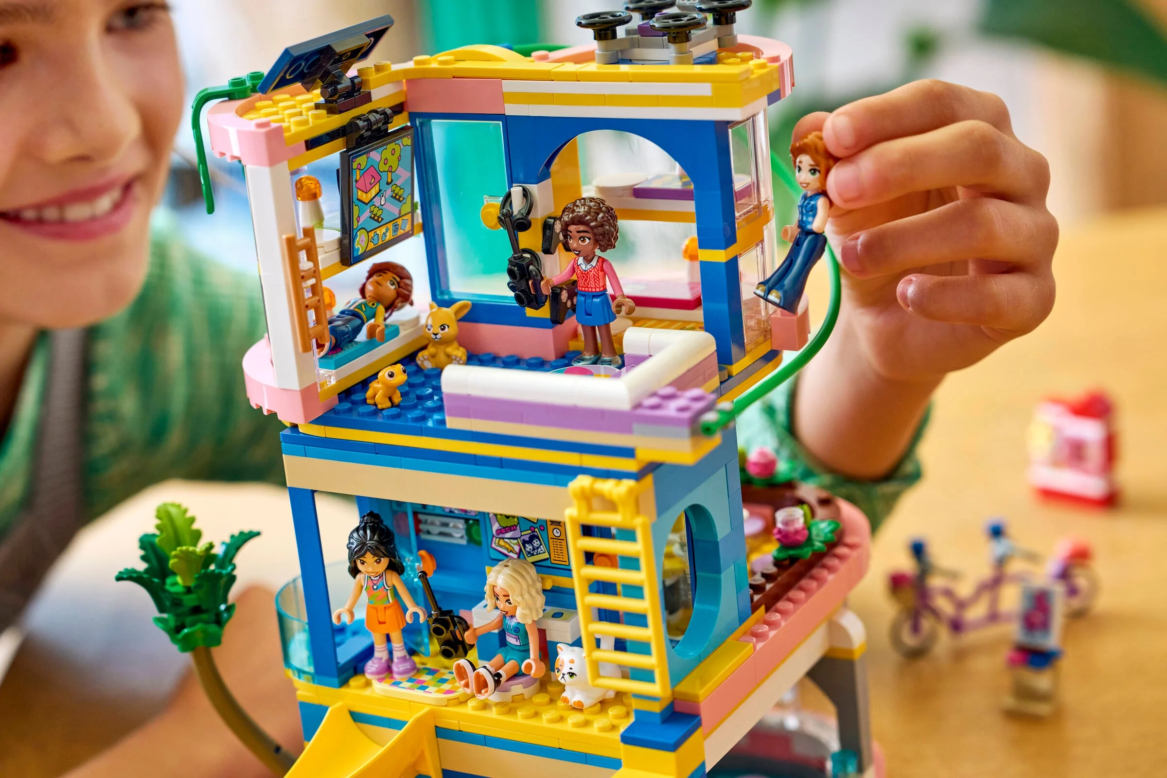 Imagine cu Club House Heartlake City. Se văd minifigurine, detalii ale construcției și un copil zâmbitor.