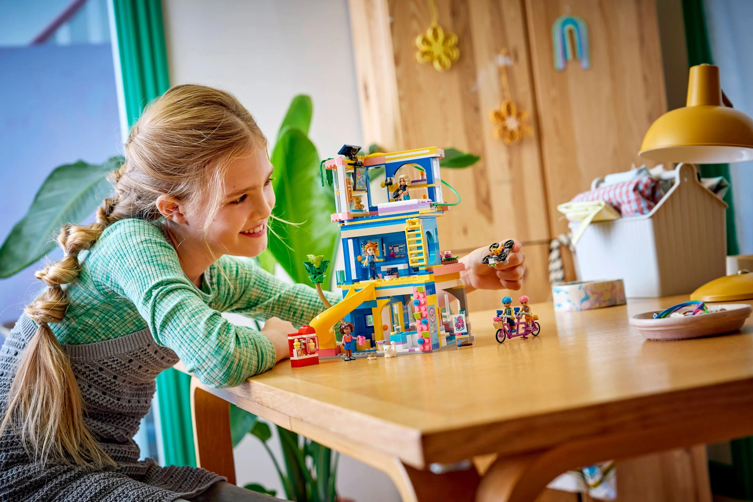 O fetiță zâmbind construiește setul LEGO Friends 42689, Club House Heartlake City.