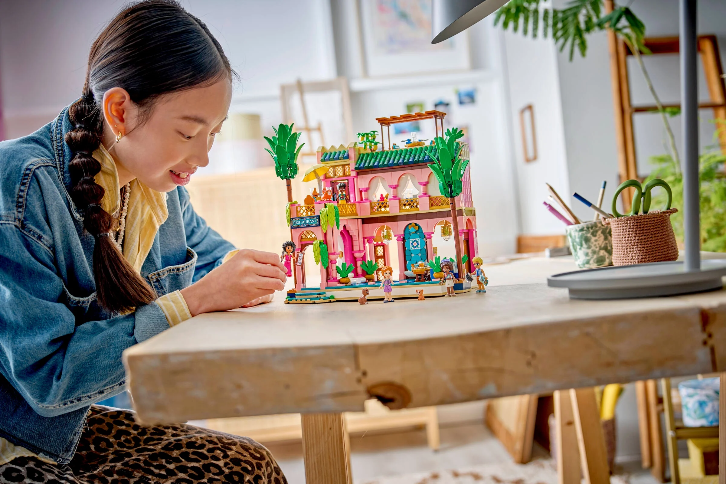Fetiță construind setul LEGO Friends Restaurant în grădină. Atmosferă creativă și primitoare.