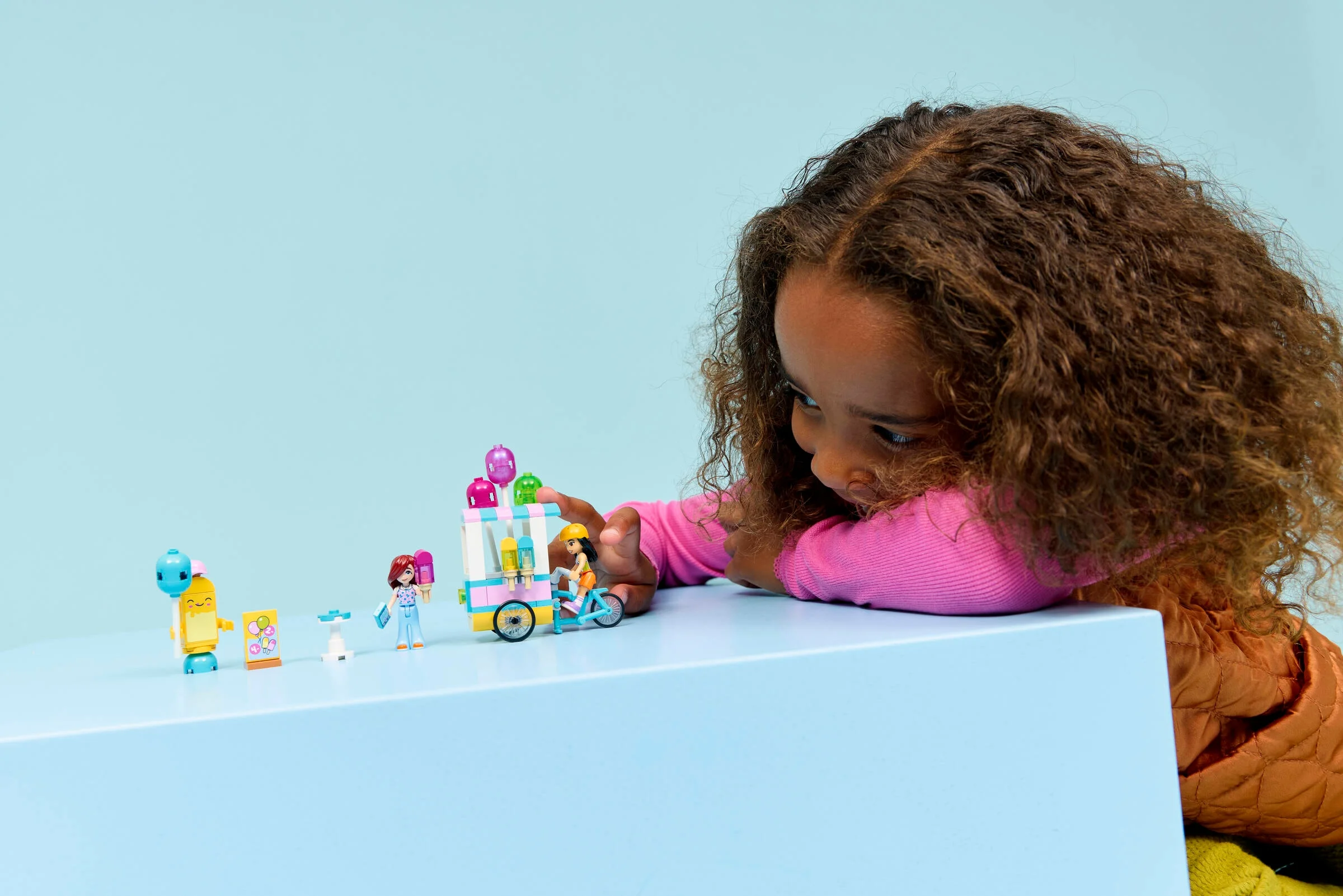 Copil se joacă cu setul LEGO Friends cu stand de înghețată și baloane. Distracție colorată!