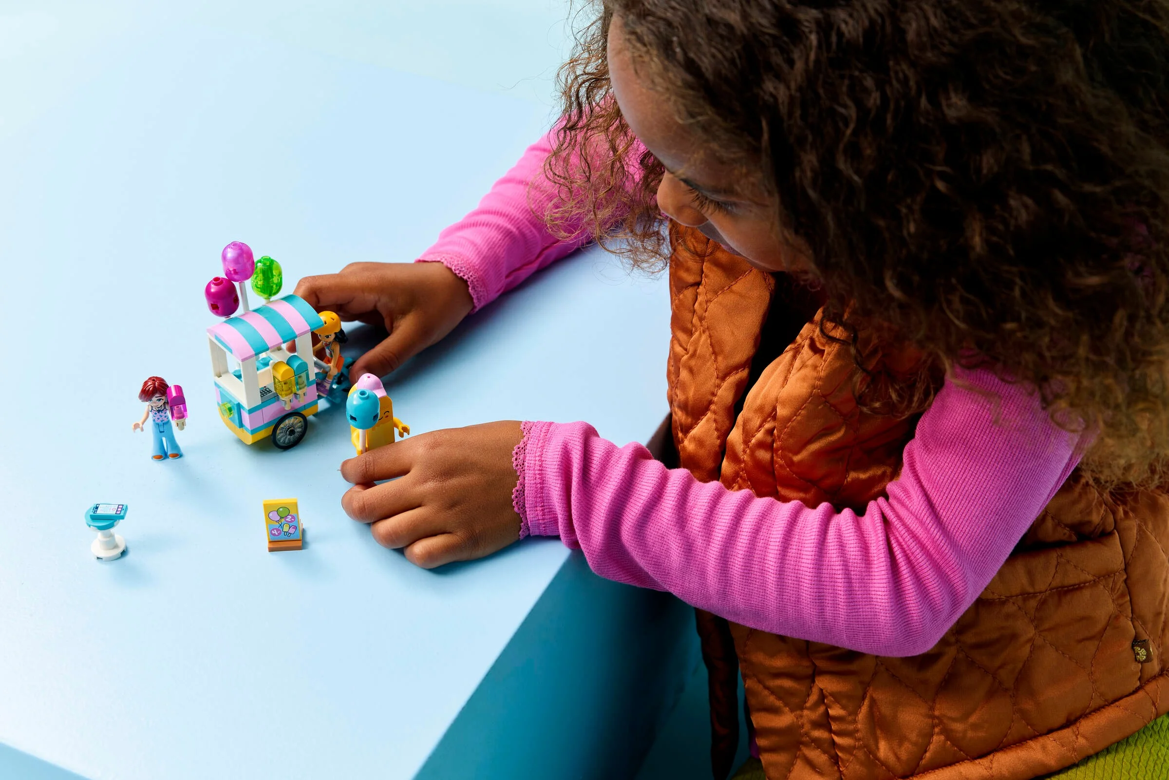 Fetiță se joacă cu standul de înghețată și baloane LEGO Friends. Distracție cu figurine și accesorii colorate.