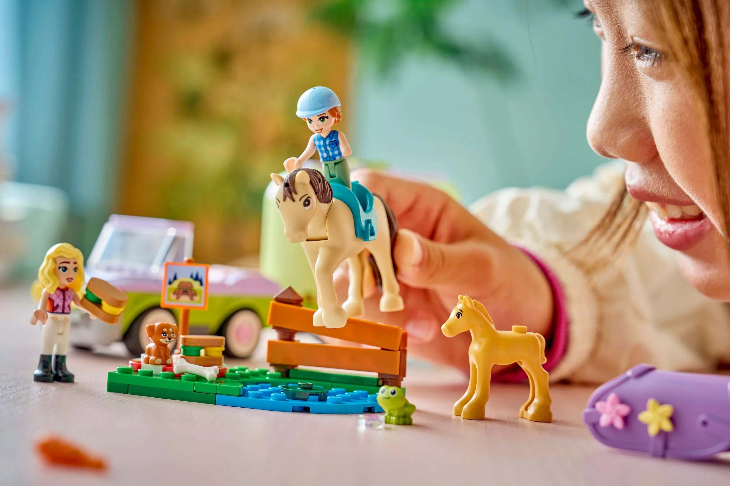 Fată jucându-se cu setul LEGO cu remorcă pentru căluți, explorând lumea fermecătoare a prieteniei și a animalelor.
