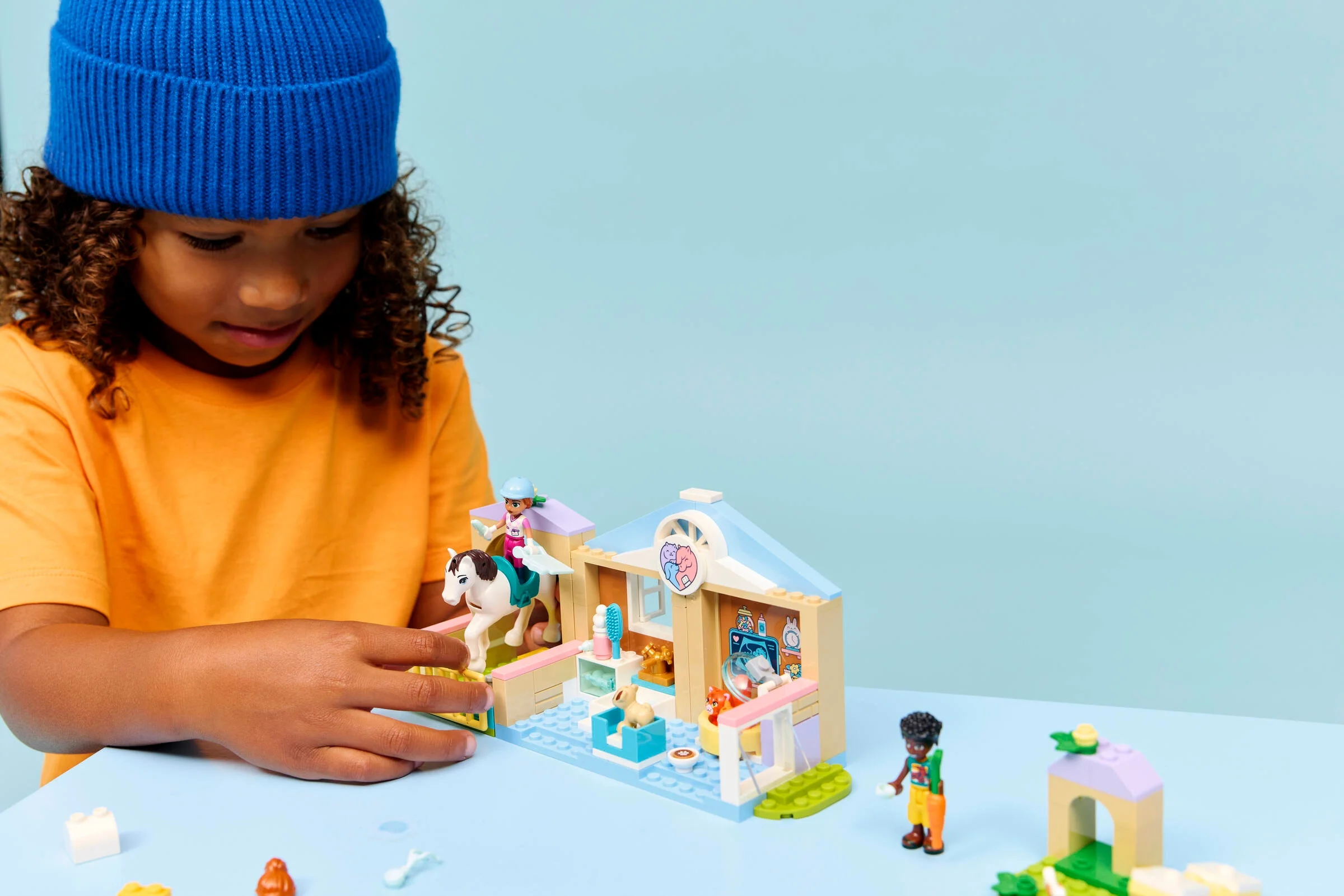 Copil construind clinica veterinară LEGO Friends. Distracție creativă cu animale și minifigurine.
