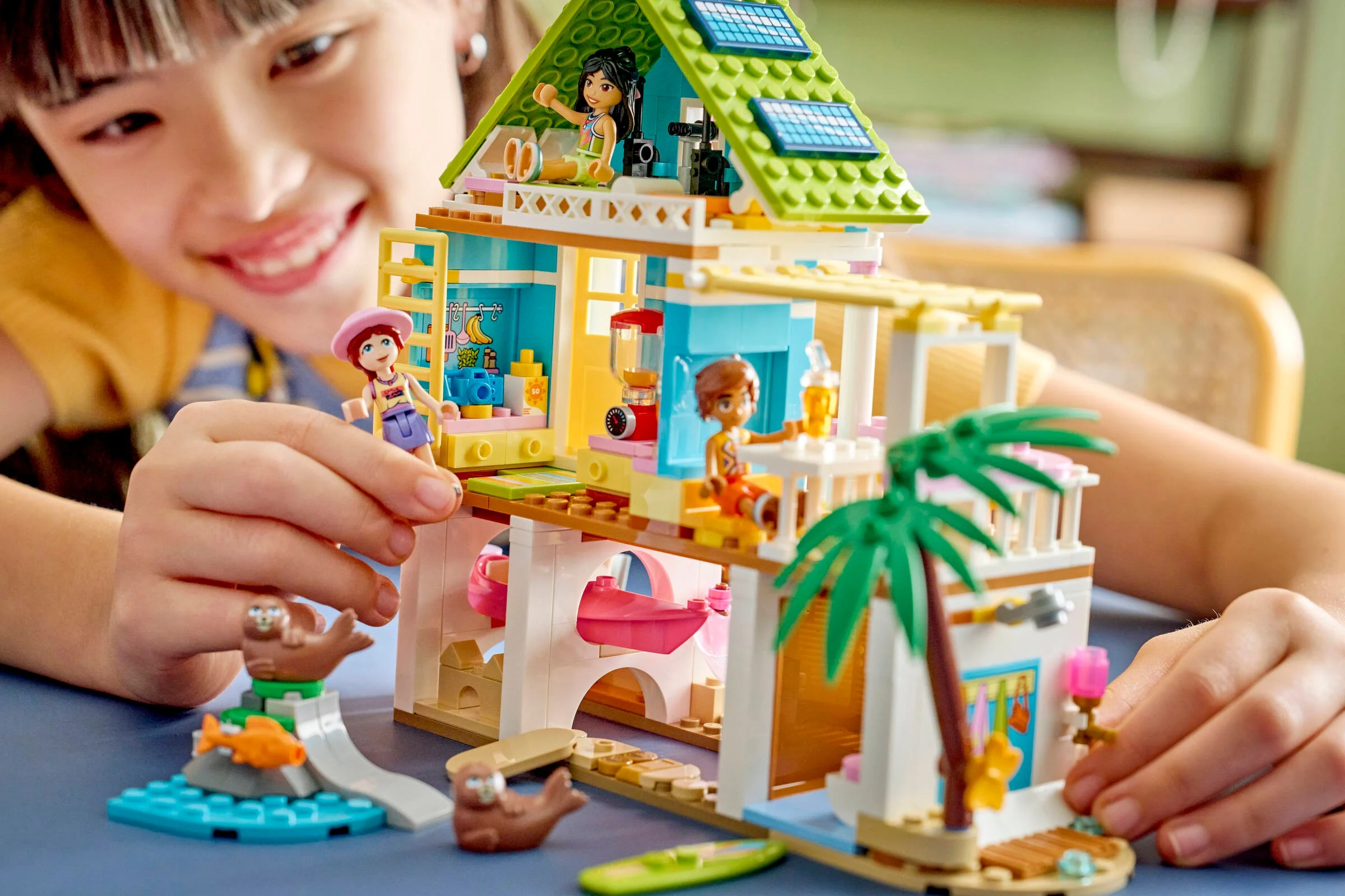 Fată zâmbitoare se joacă cu setul LEGO Friends 42699, Casa de pe plajă cu foci.