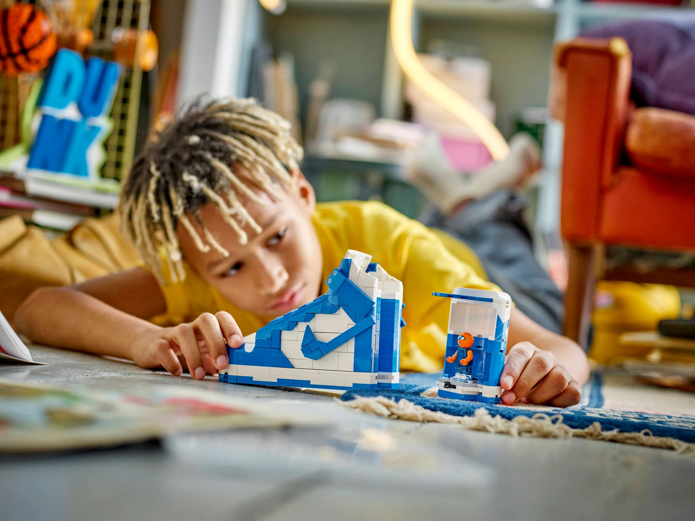 Băiat construind modelul LEGO Nike Dunk albastru și alb. Detaliu cu minifigurina.