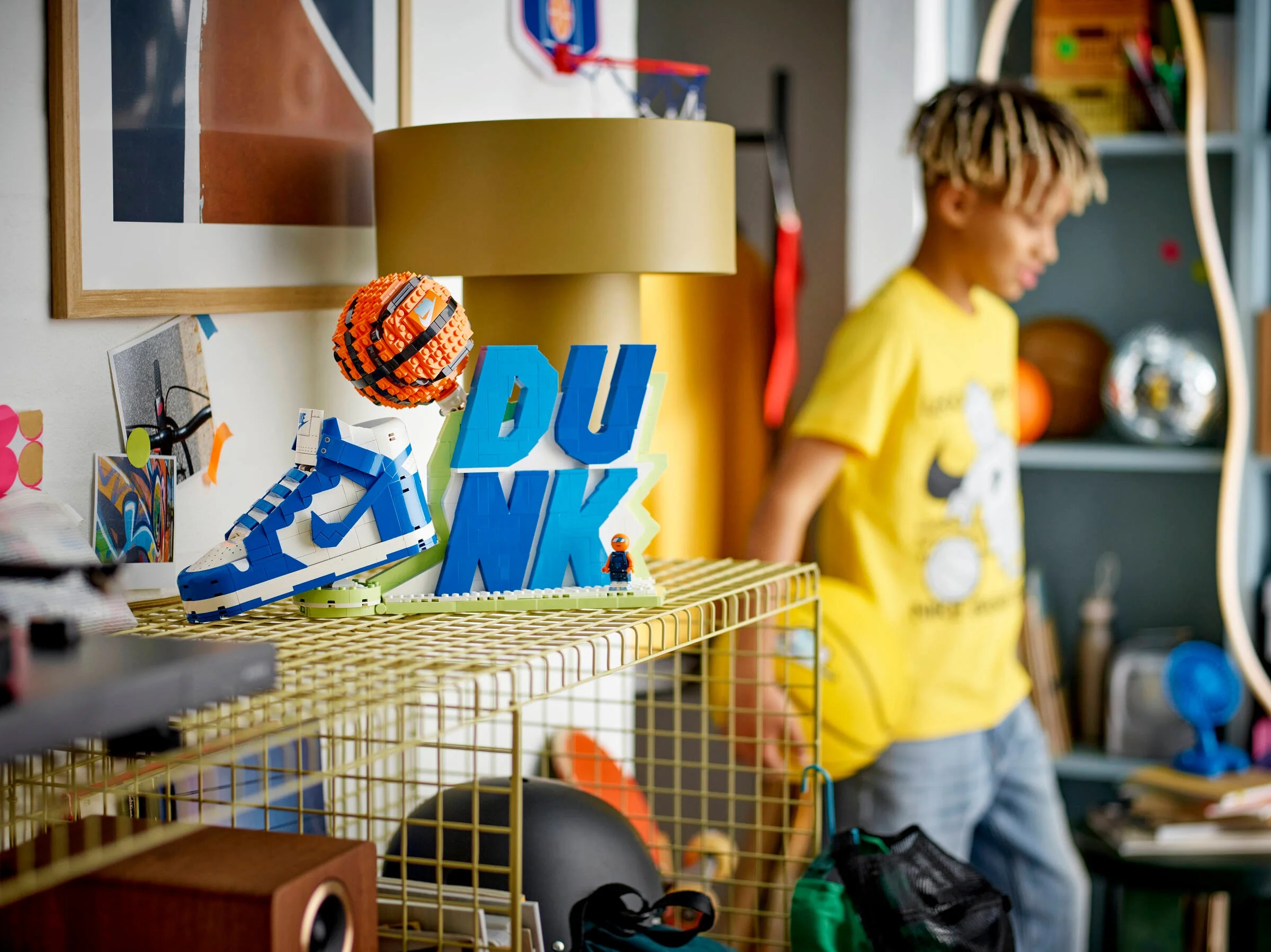 Modelul LEGO Nike Dunk expus într-o cameră, cu un copil în fundal.