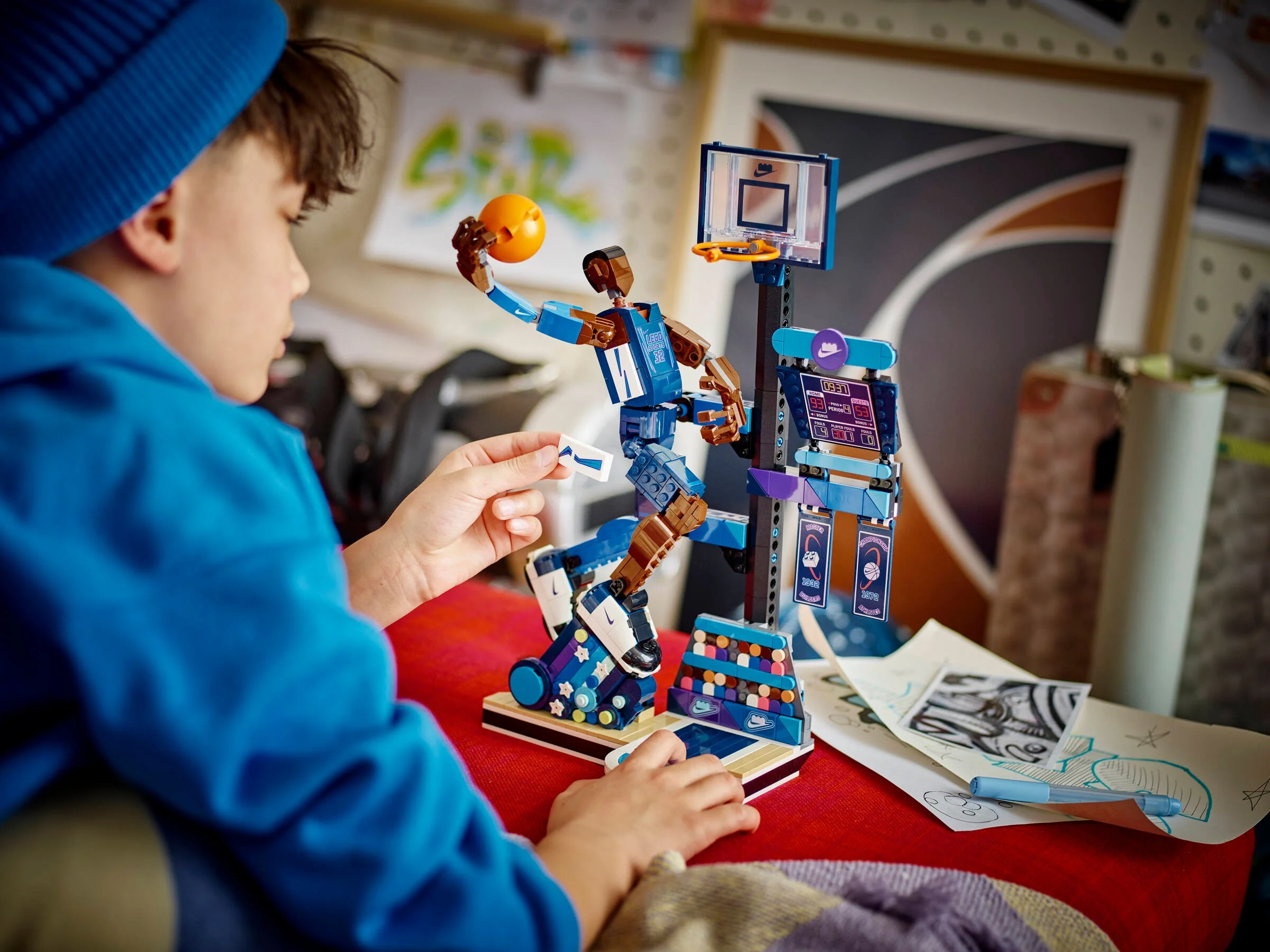 Un copil montează setul LEGO Nike Slam Dunk, modelul fiind vizibil pe masă.