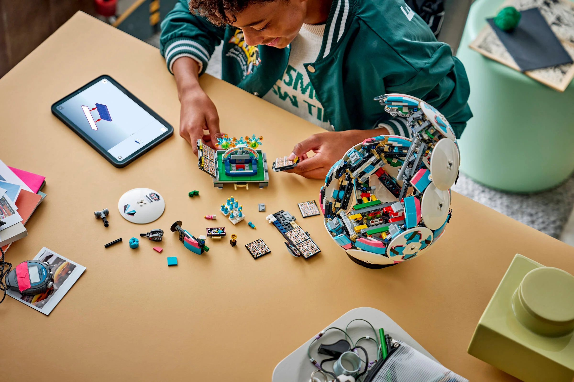 Un copil construiește stadionul și mingea din setul LEGO 43019, urmând instrucțiunile digitale.