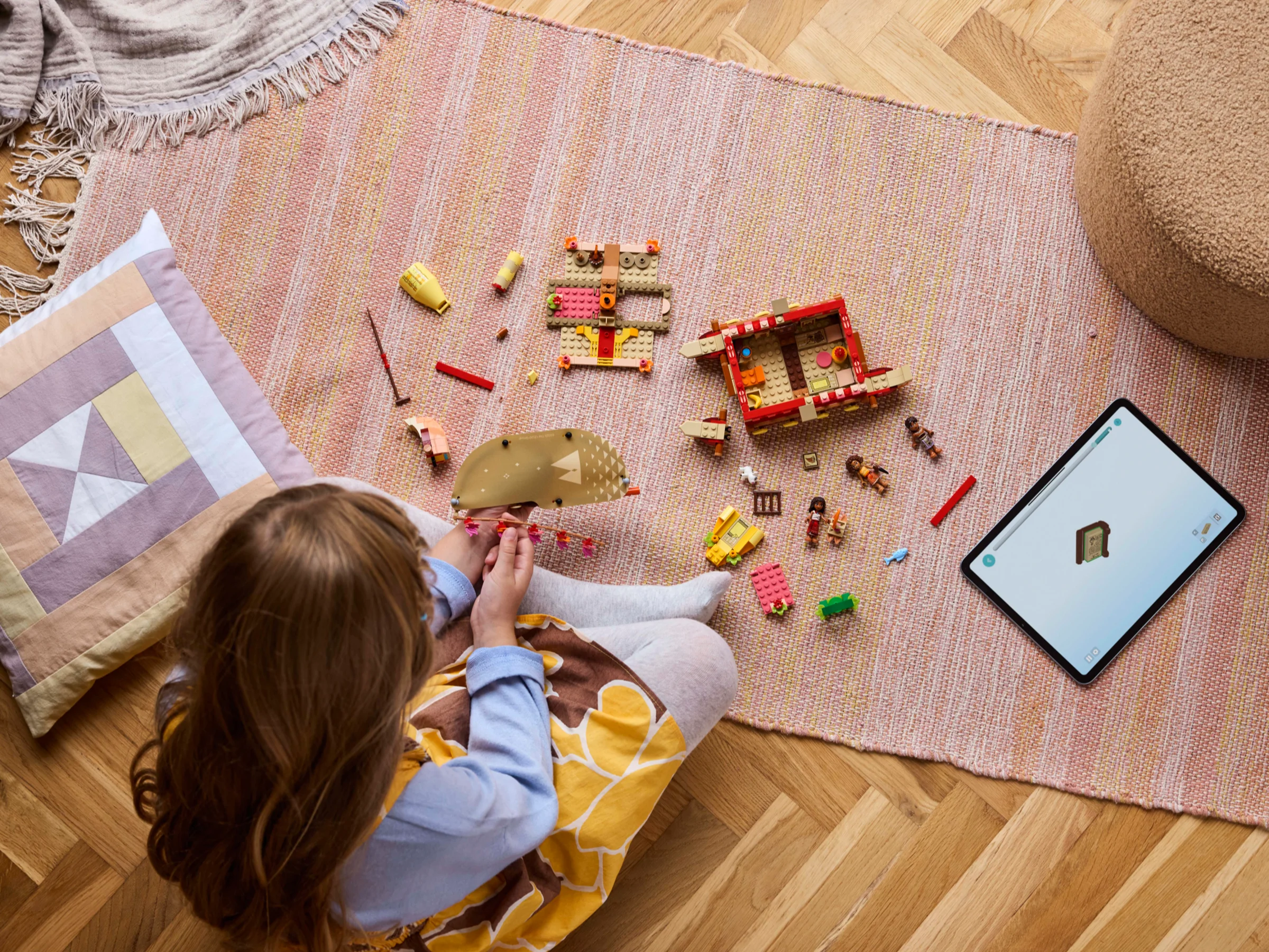 Fetiță construind setul LEGO Moana cu instrucțiuni digitale pe tabletă.