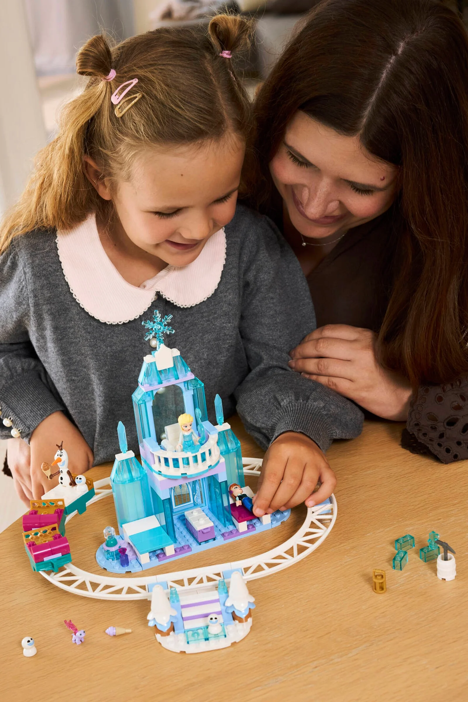 Fetiță și mamă se joacă cu castelul de gheață LEGO al Elsei, explorând aventura magică.