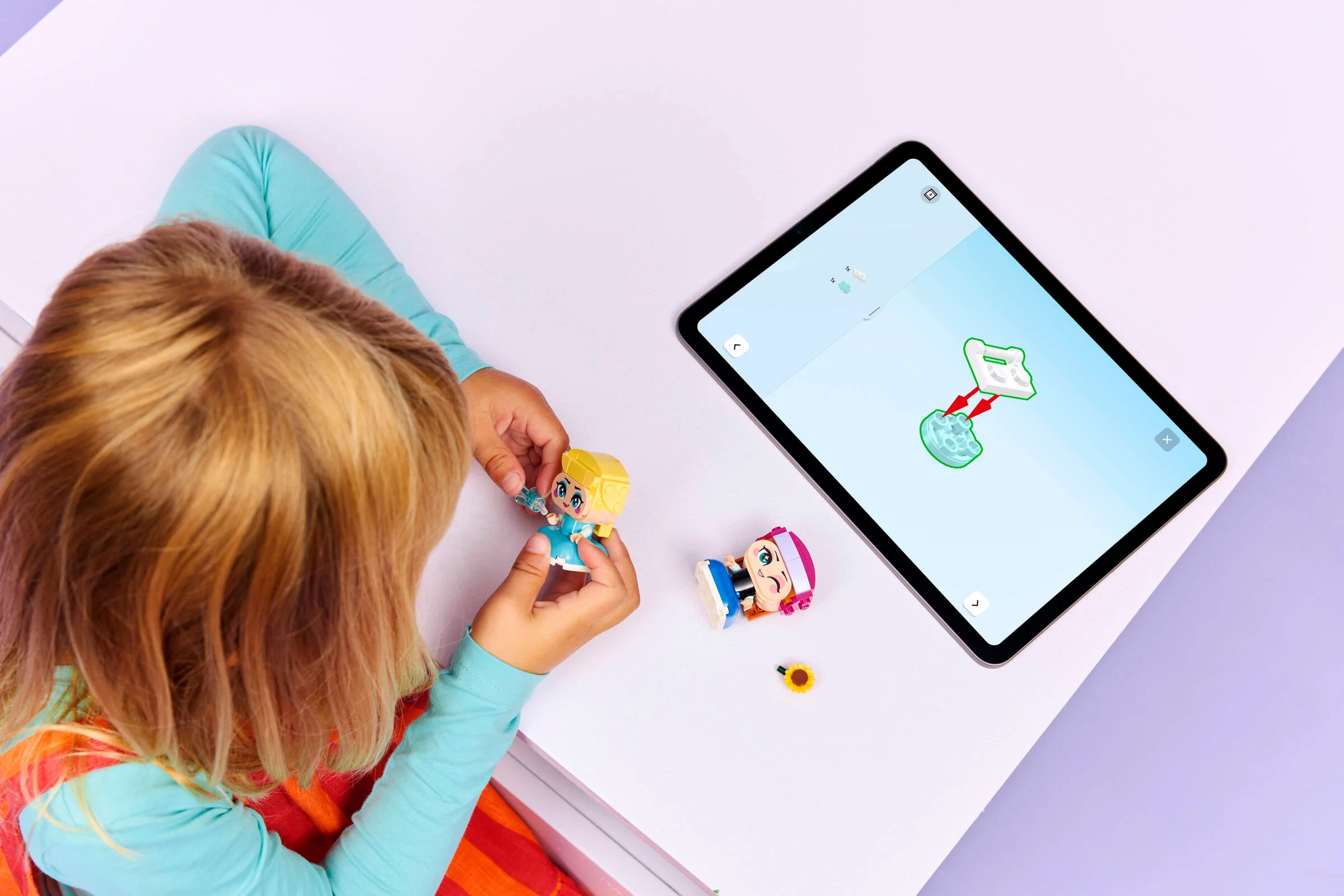 Copil asamblând setul Mini Anna și Elsa, folosind instrucțiuni digitale pe tabletă.