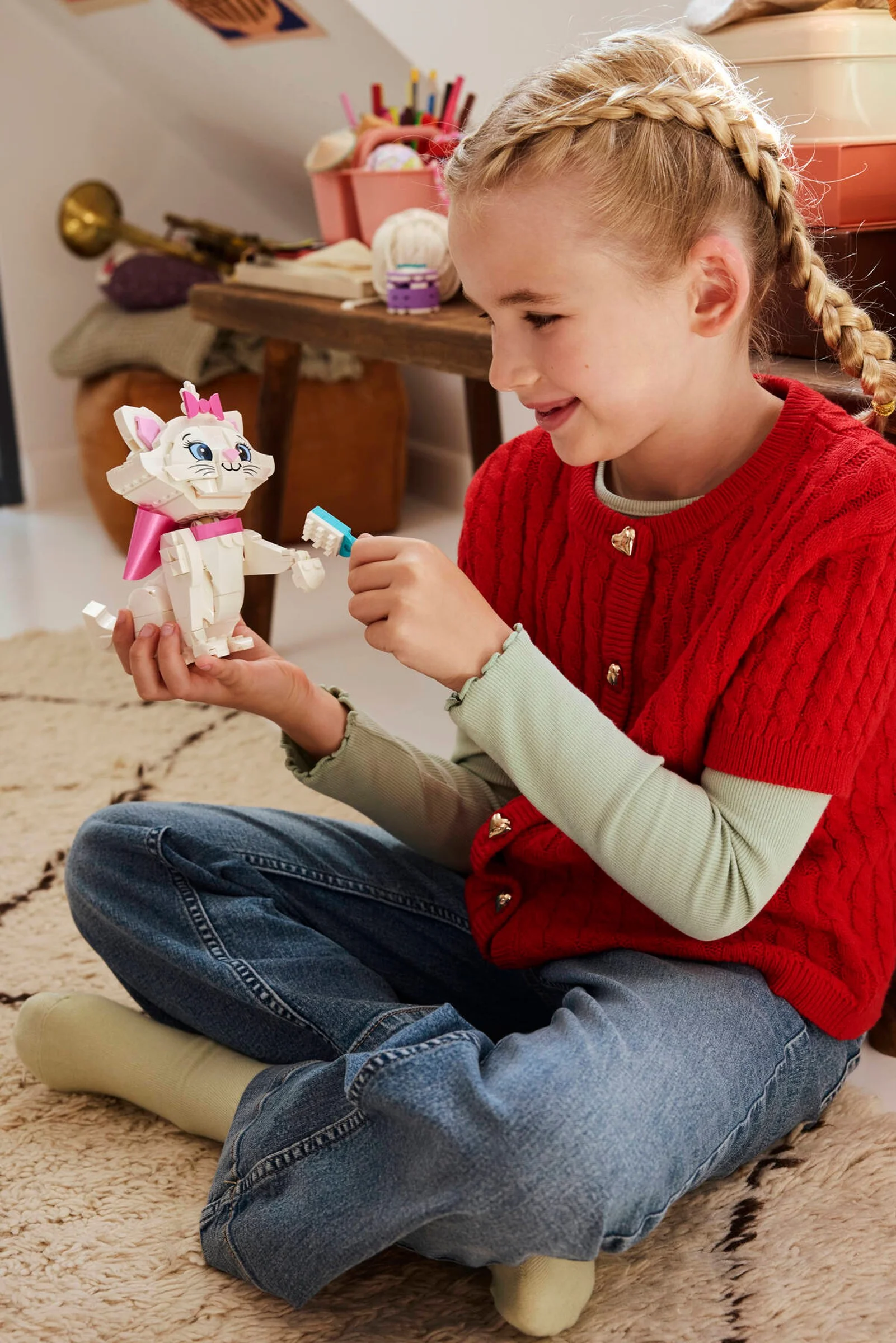 O fetiță zâmbitoare se joacă cu setul LEGO Marie, perindu-i blănița cu o perie mică.