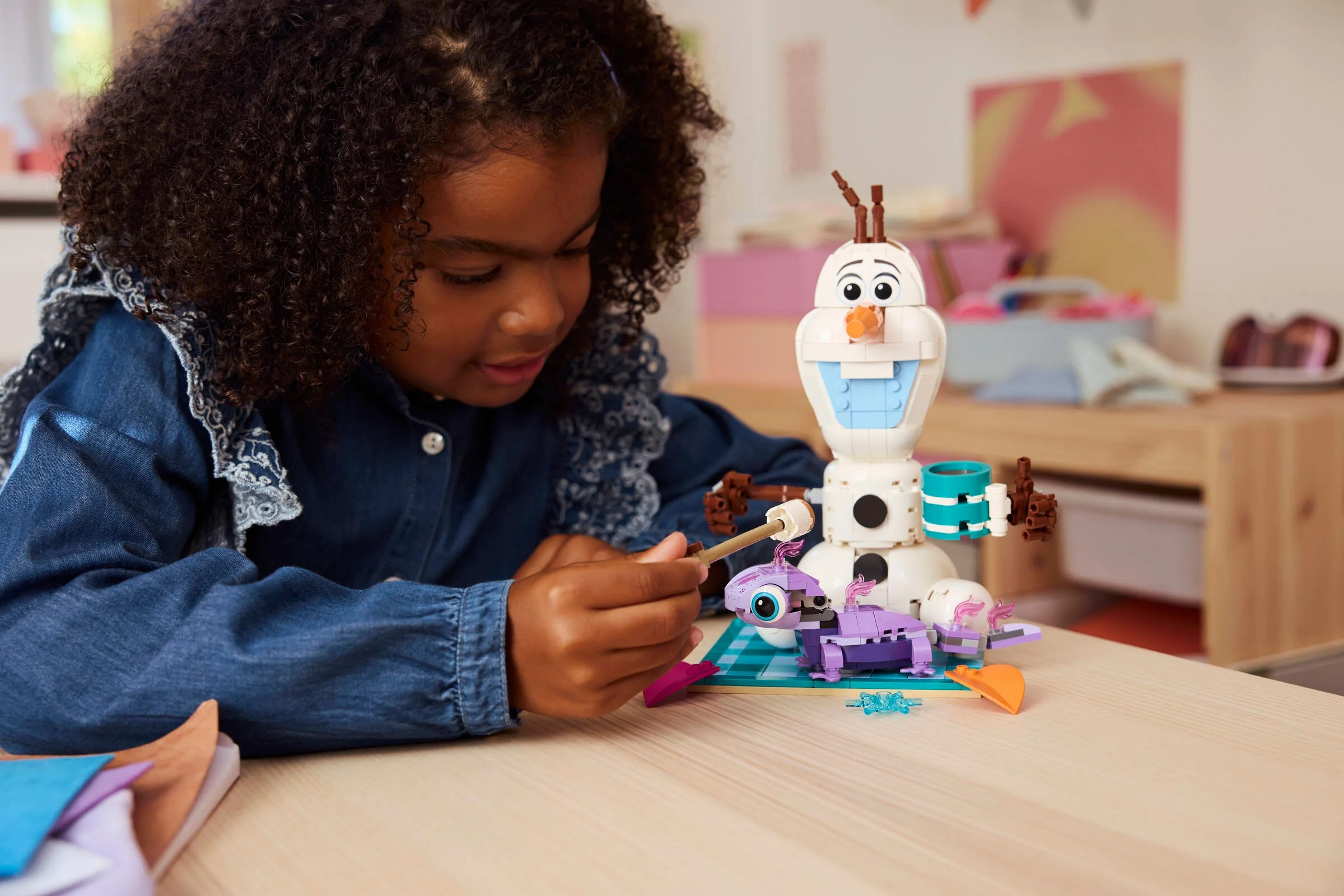 O fată se joacă cu setul LEGO 43287, Olaf și picnicul lui Bruni. Modelul este parțial asamblat.