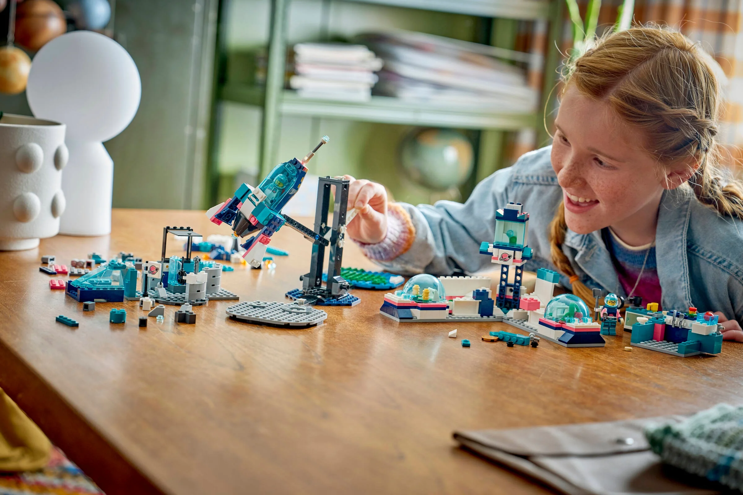 Fată construind cu setul LEGO Misiune pe Lună. Zâmbetul reflectă bucuria explorării.