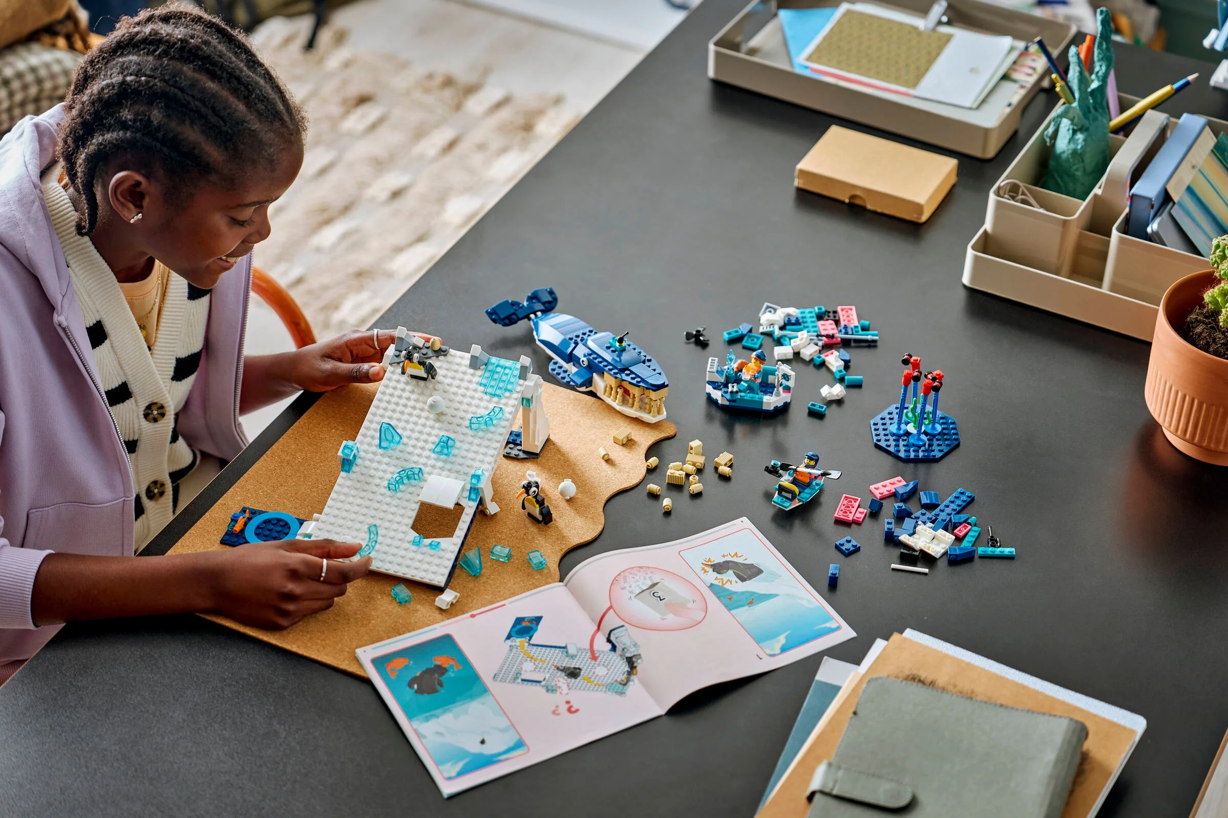 Copil construind setul LEGO Antarctic Animals. Include balenă, pinguini, iceberg și instrucțiuni.