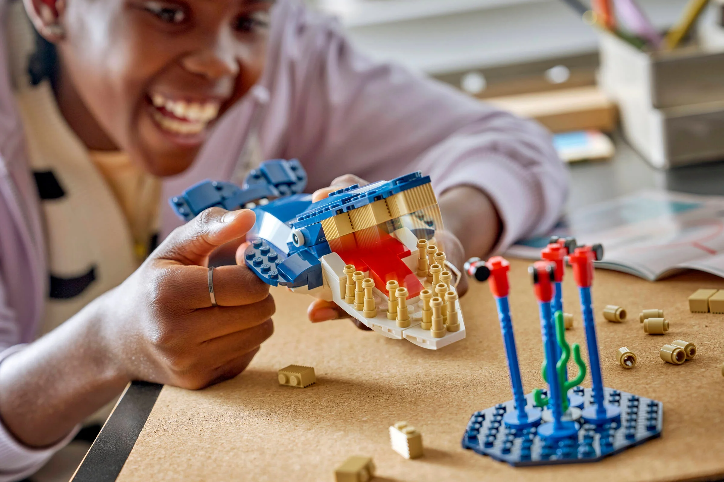 Fetiță zâmbitoare ținând o balenă LEGO albastră. Setul Antarctic Animals este distractiv și educativ.