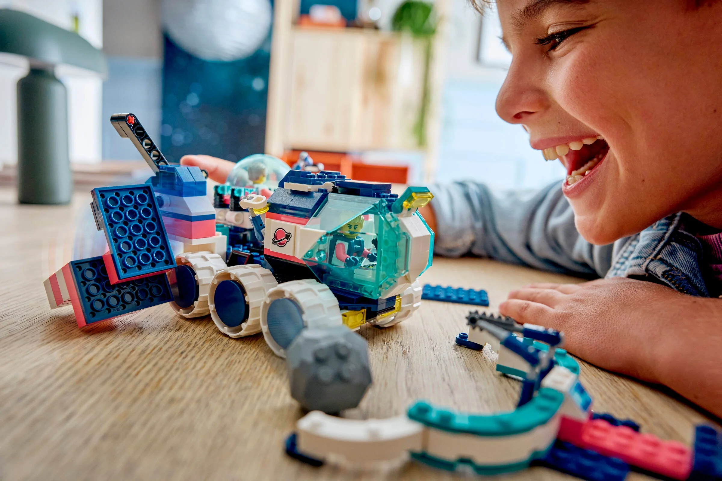 Un copil entuziasmat se joacă cu roverul LEGO din setul Mars Mission.
