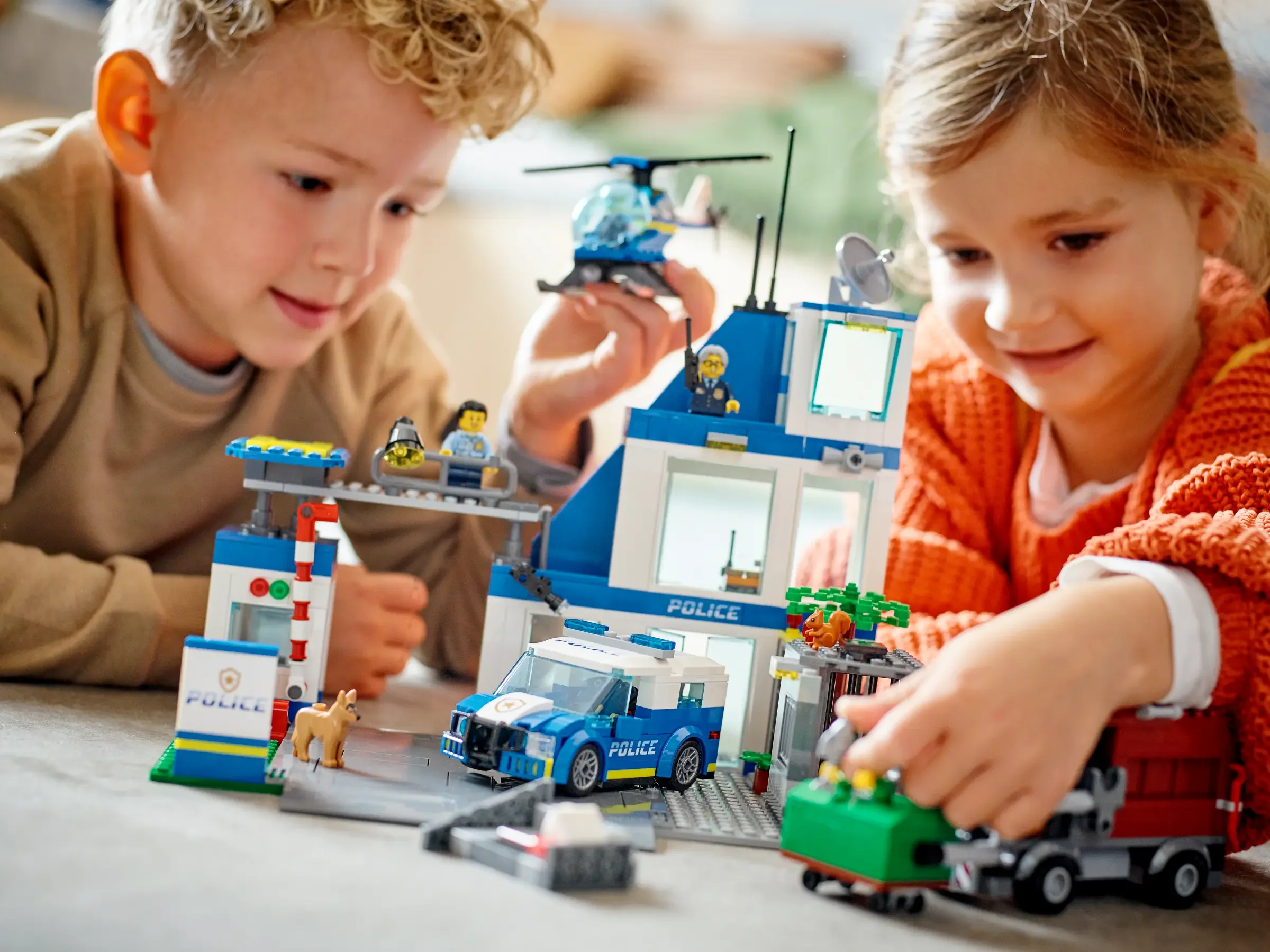 Copii se joacă cu setul LEGO City 60316, Stație de Poliție. O scenă plină de acțiune și zâmbete.