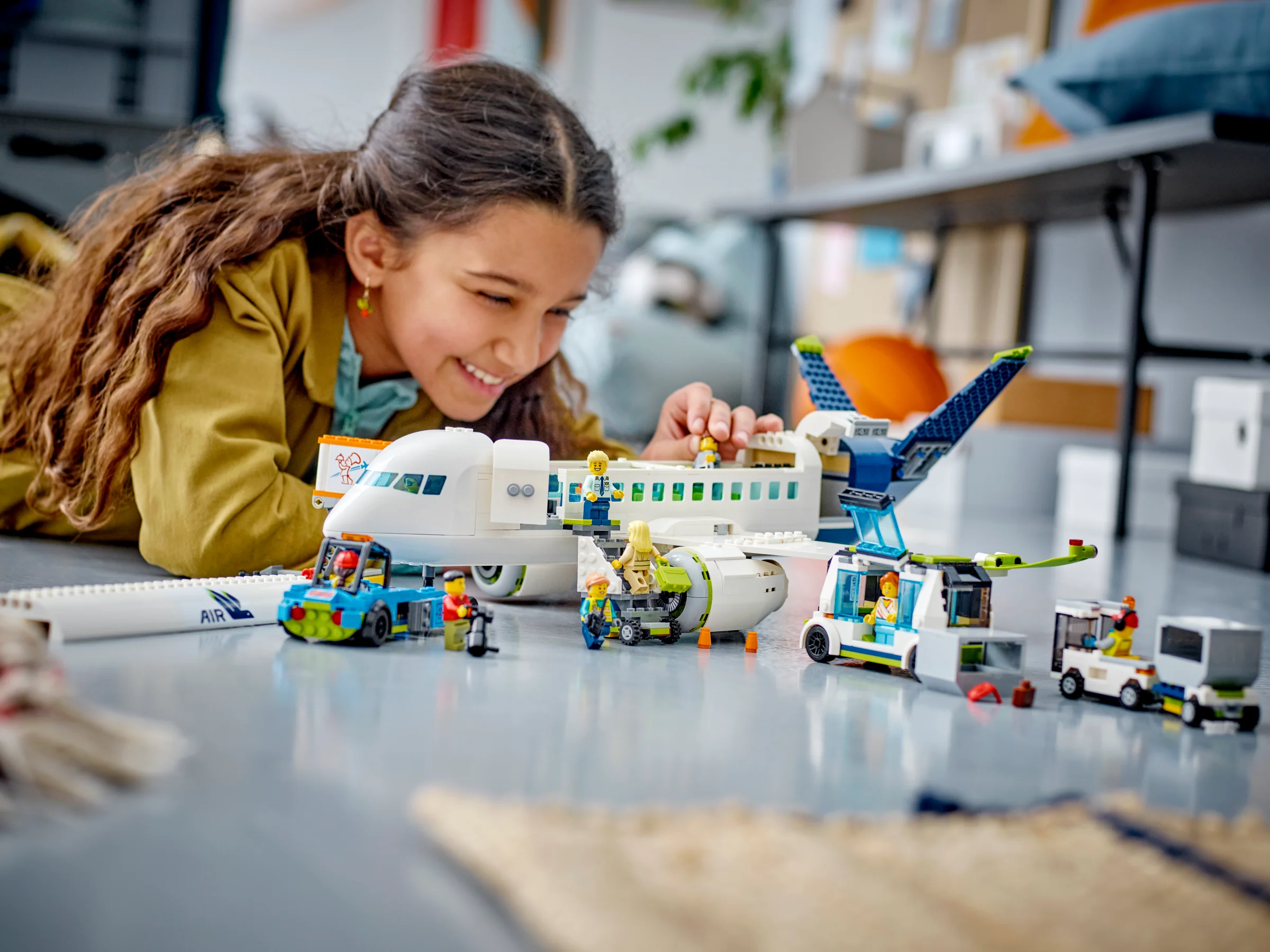 Fetiță zâmbitoare se joacă cu avionul de pasageri LEGO City, explorând lumea aviației.