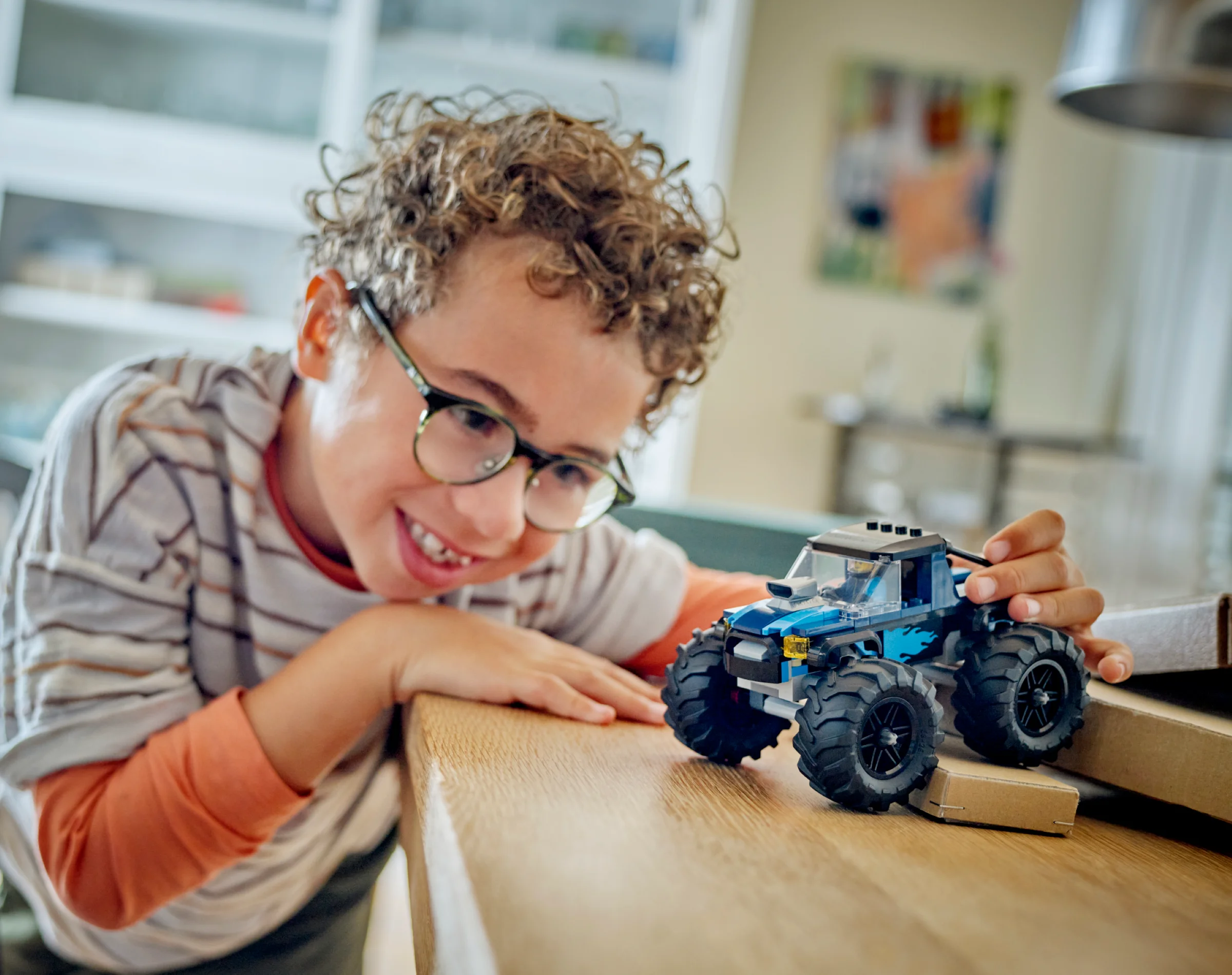 Un copil zâmbește jucându-se cu camionul monstru LEGO 60402.