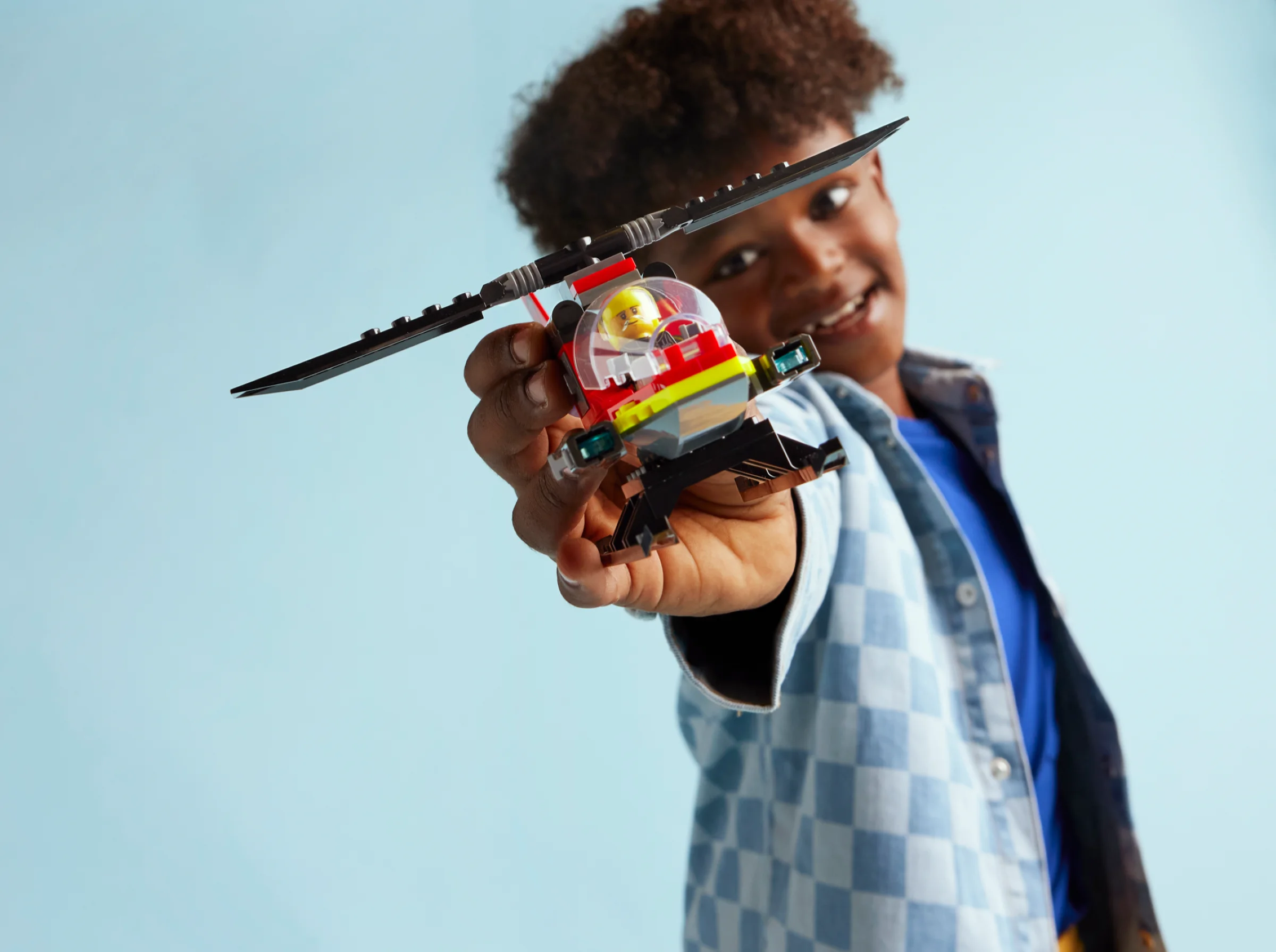 Băiat zâmbitor prezintă elicopterul de salvare LEGO City. Distracție și aventură cu pompierii curajoși!