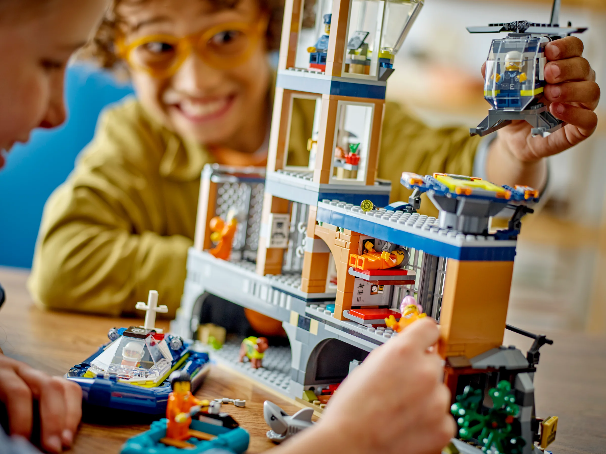 Imagine detaliată cu Insula Închisoare, elicopter, barcă și figurine, cu copii jucându-se.