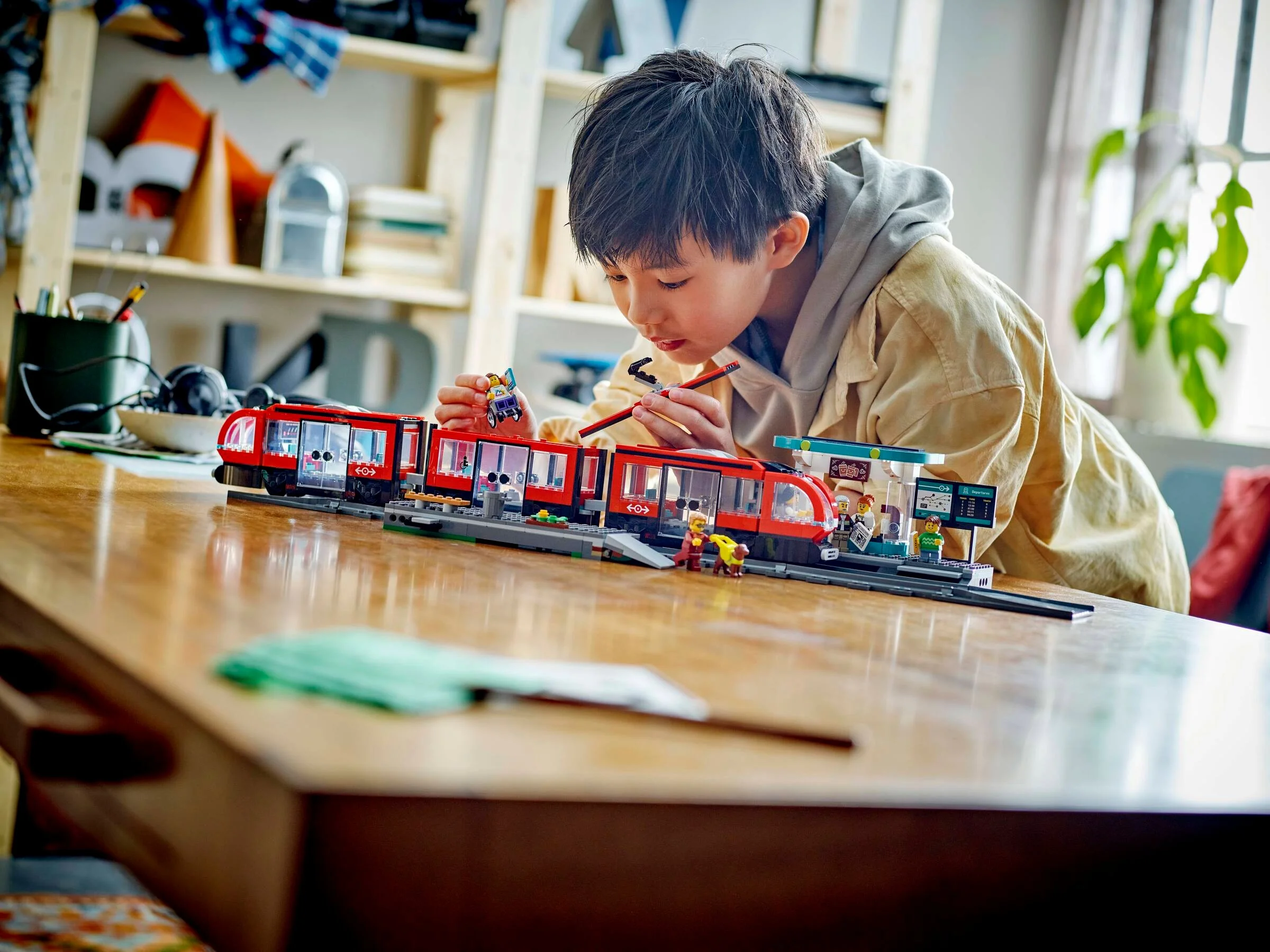 Băiat construind tramvaiul LEGO 60423, concentrat la detalii.