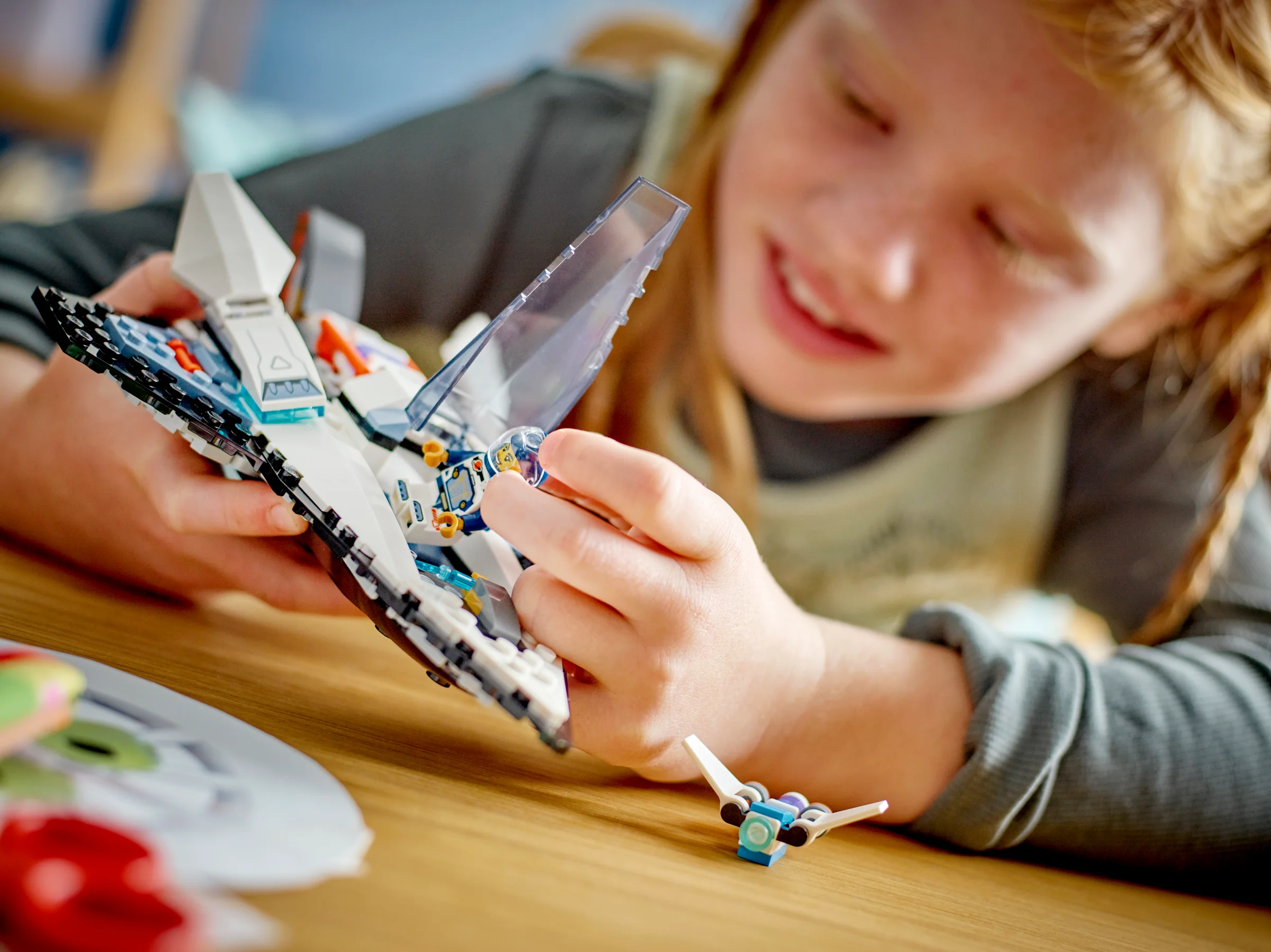 Fetiță zâmbitoare se joacă cu nava spațială LEGO, introducând un astronaut.