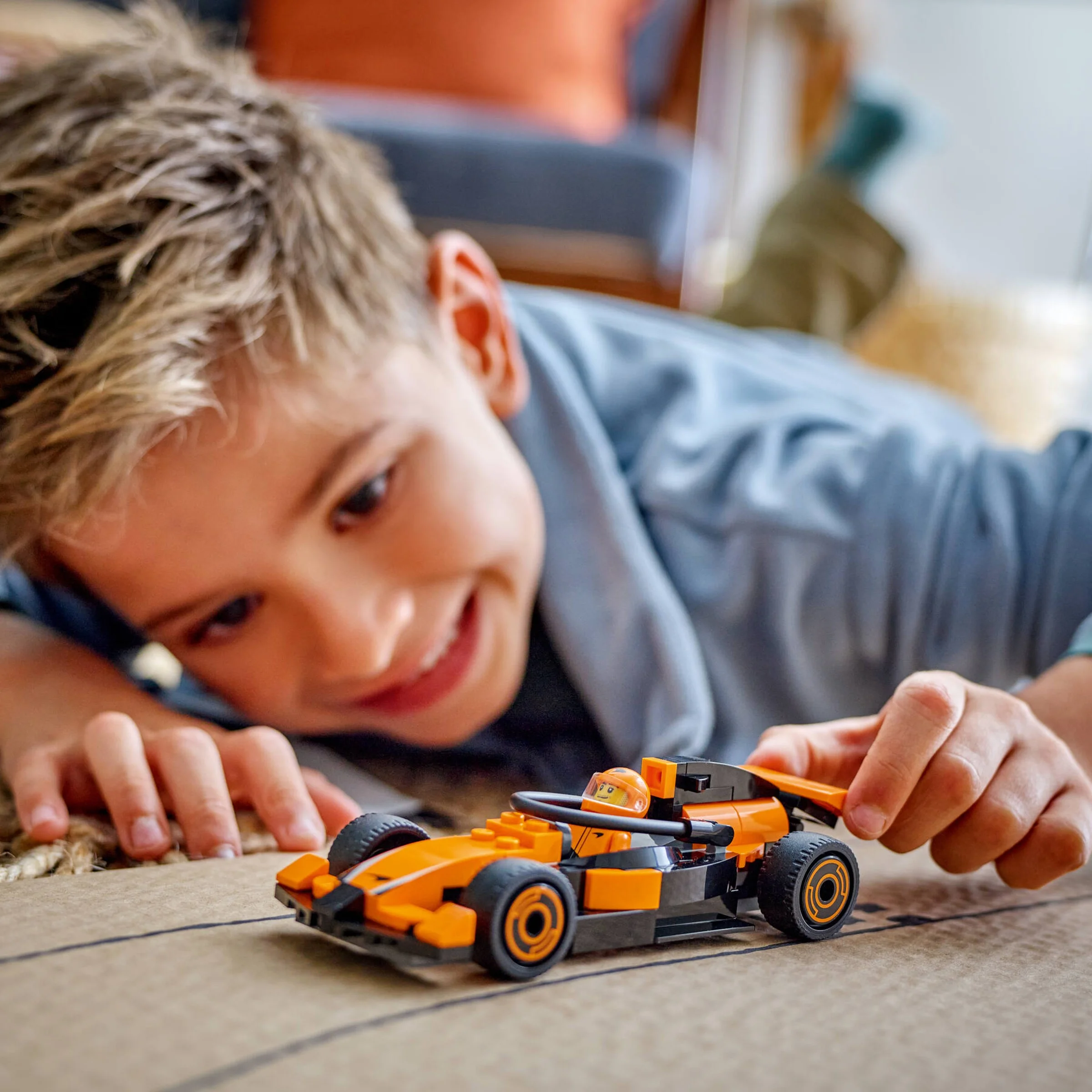 Copil zâmbitor joacă cu mașina de curse McLaren LEGO, concentrat și entuziasmat.