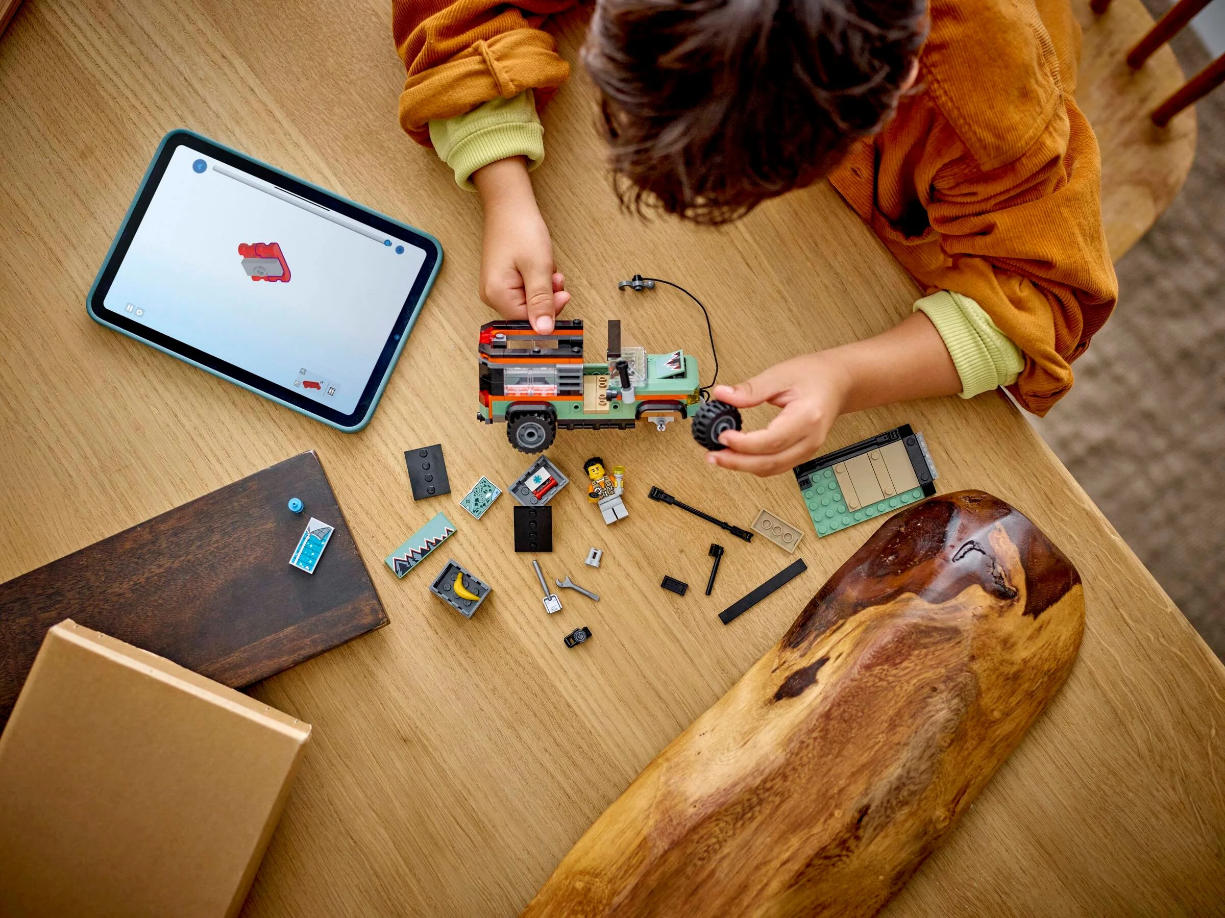 Copil construind camionul LEGO 60447 urmând instrucțiuni digitale pe tabletă. Distracție creativă cu jucării LEGO.