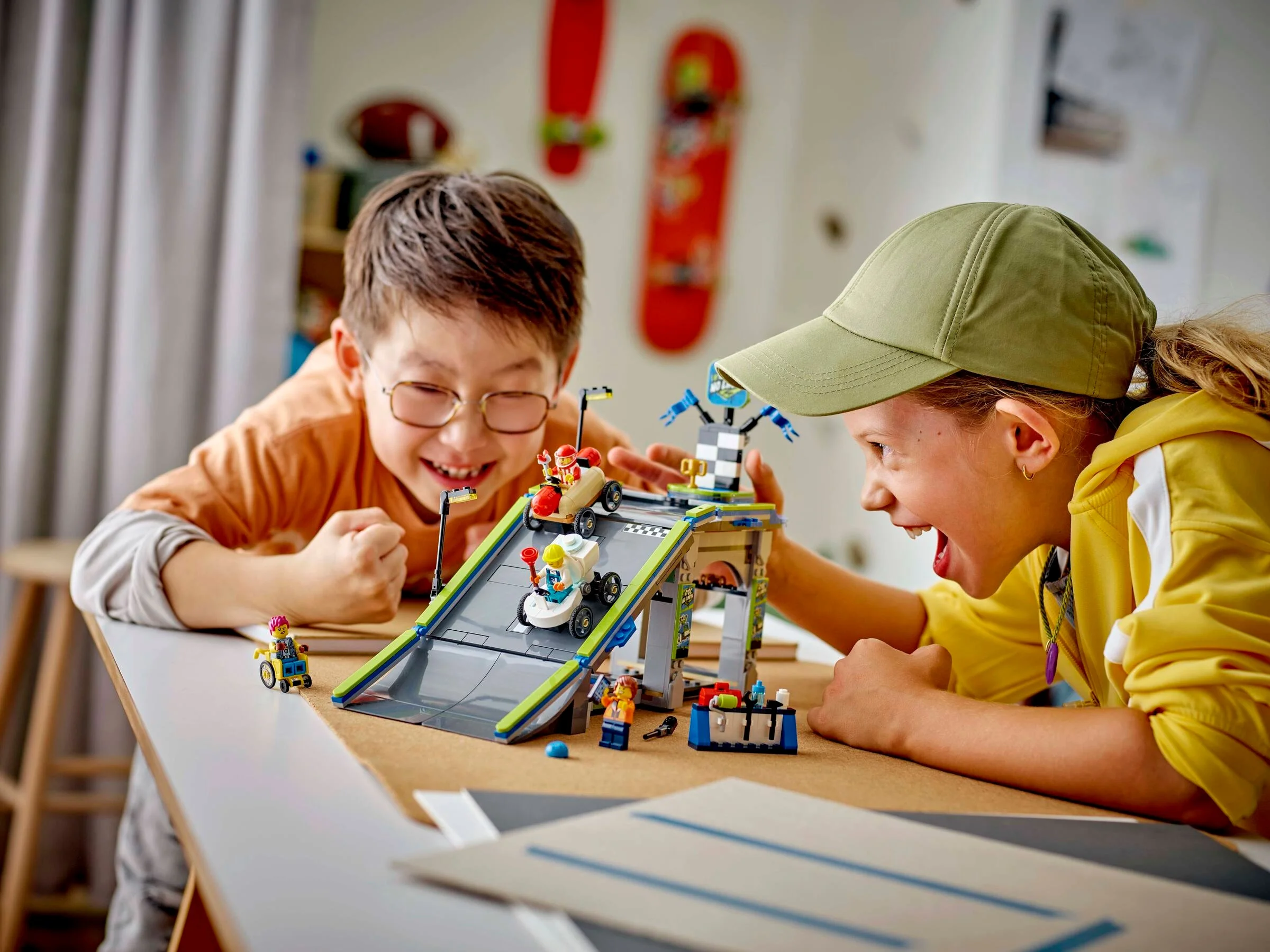Doi copii entuziasmați se joacă cu rampa și mașinile de curse LEGO City.