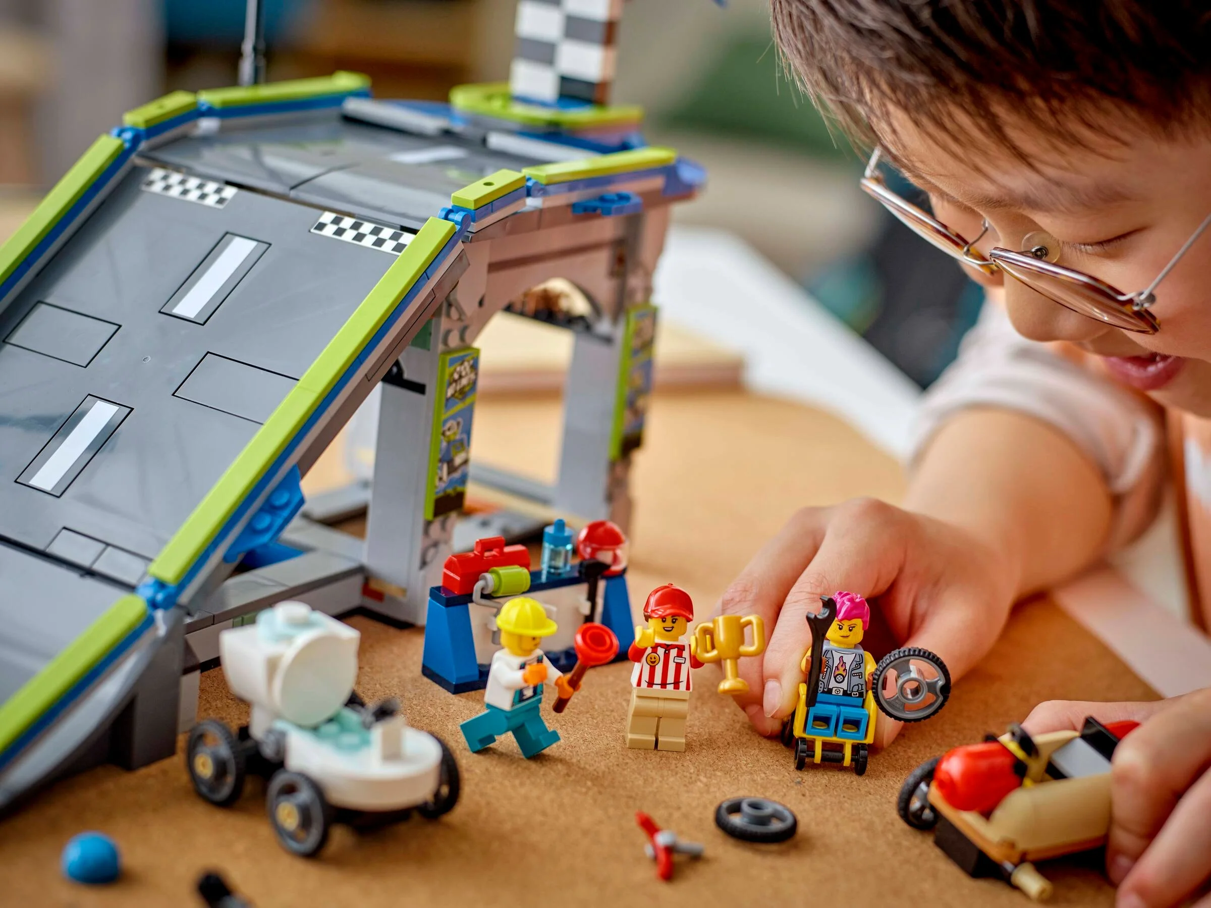 Imagine cu o rampă de curse LEGO City și minifigurine, copil interacționând.