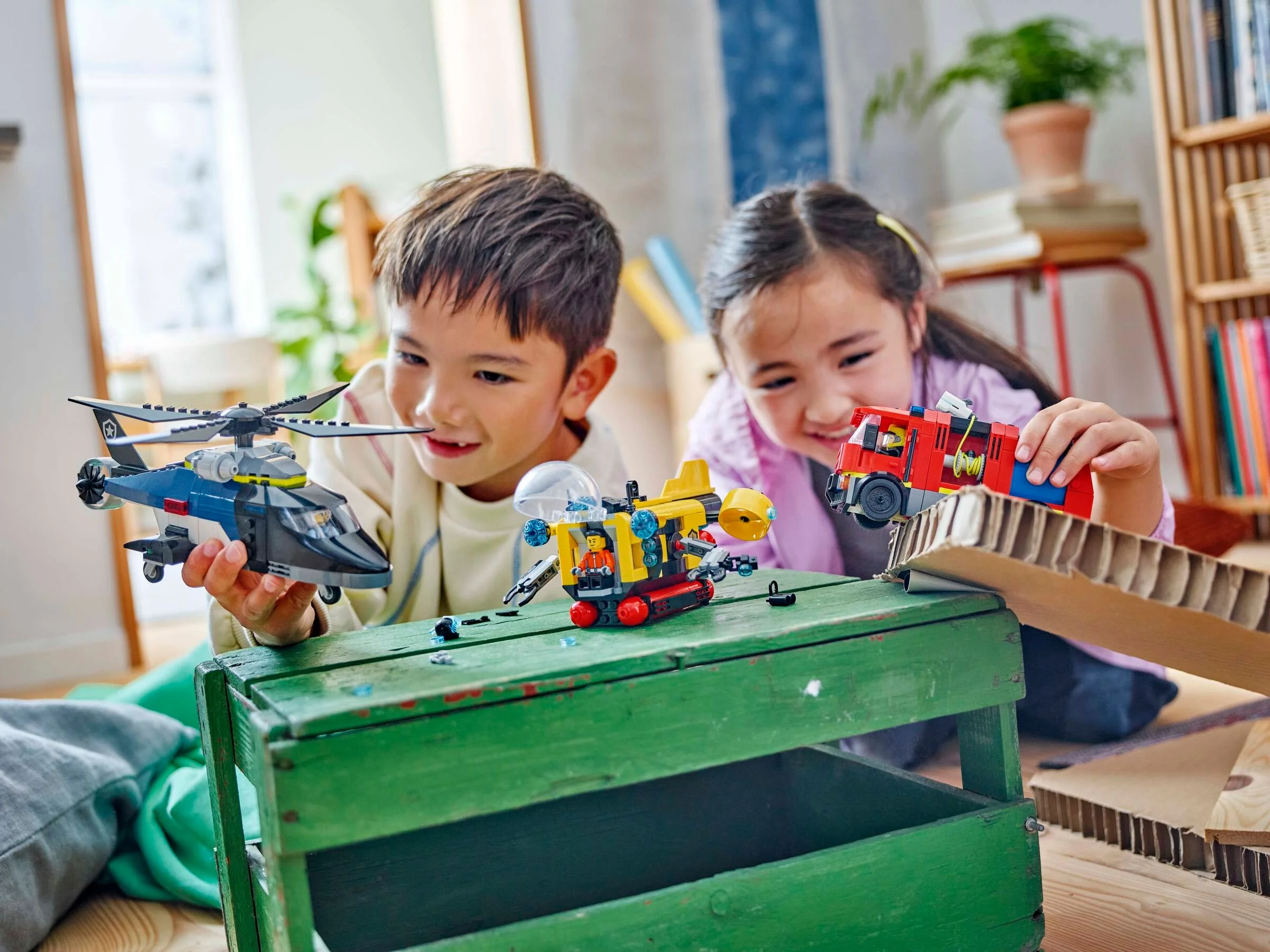 Copii jucându-se cu setul LEGO 60462, elicopter, camion de pompieri și submarin.