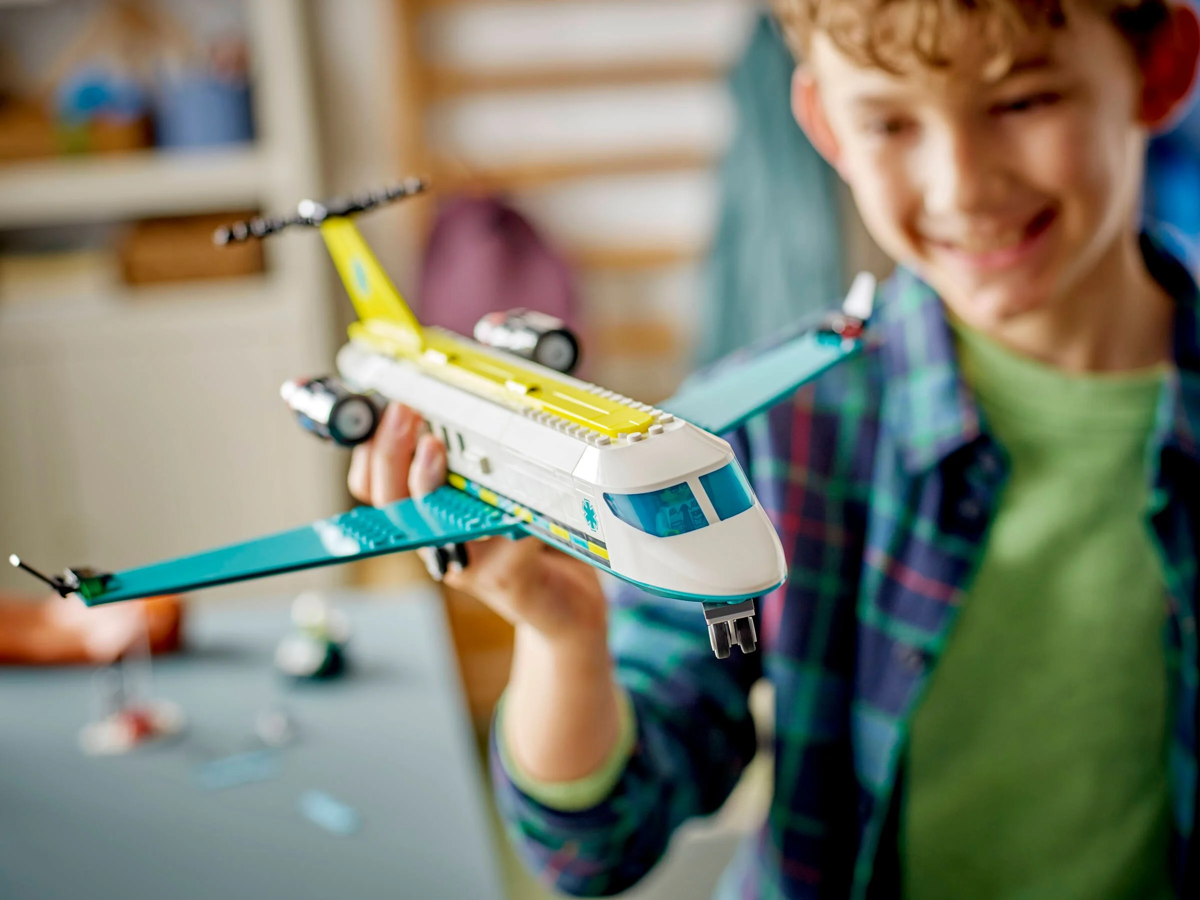 Băiat zâmbitor ținând avionul medical LEGO, City 60465. Jucărie detaliată.