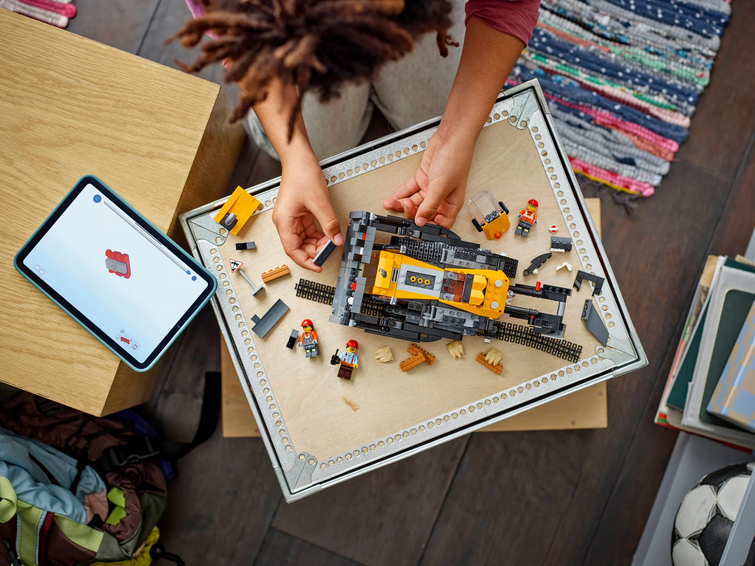 Construirea unui buldozer LEGO City. Vedere de sus cu instrucțiuni pe tabletă.