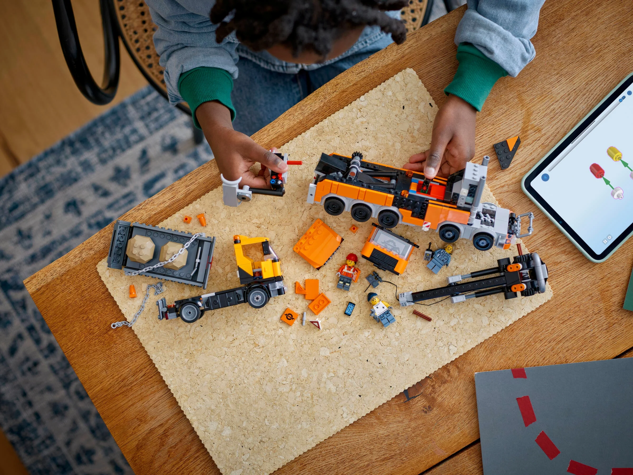 Copil asamblează camionul de remorcare LEGO 60467, folosind instrucțiuni de pe tabletă.
