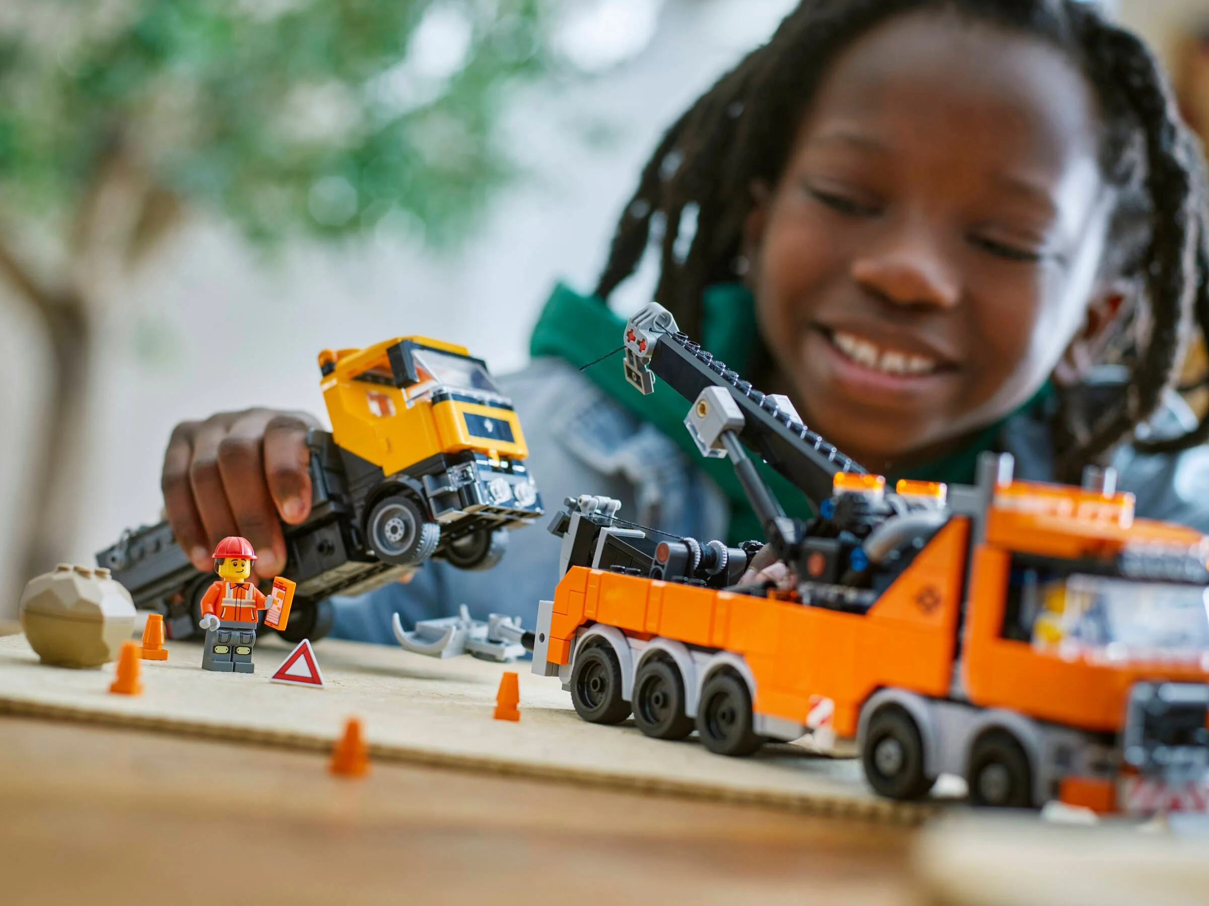 Copil zâmbitor se joacă cu camionul de remorcare LEGO City. O scenă distractivă și interactivă.