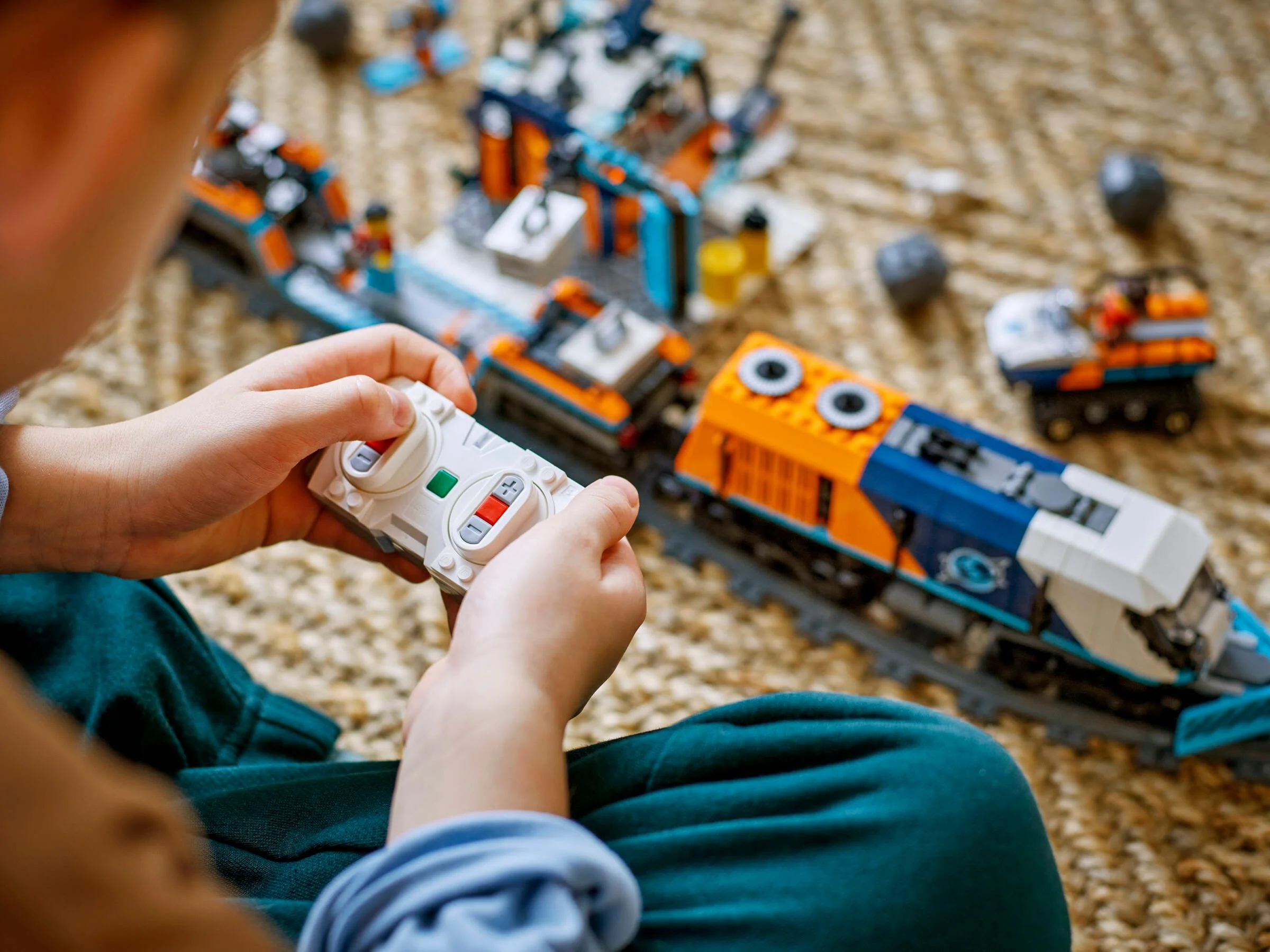 Copil controlează trenul Explorer LEGO® cu telecomanda. Setul este colorat și detaliat.