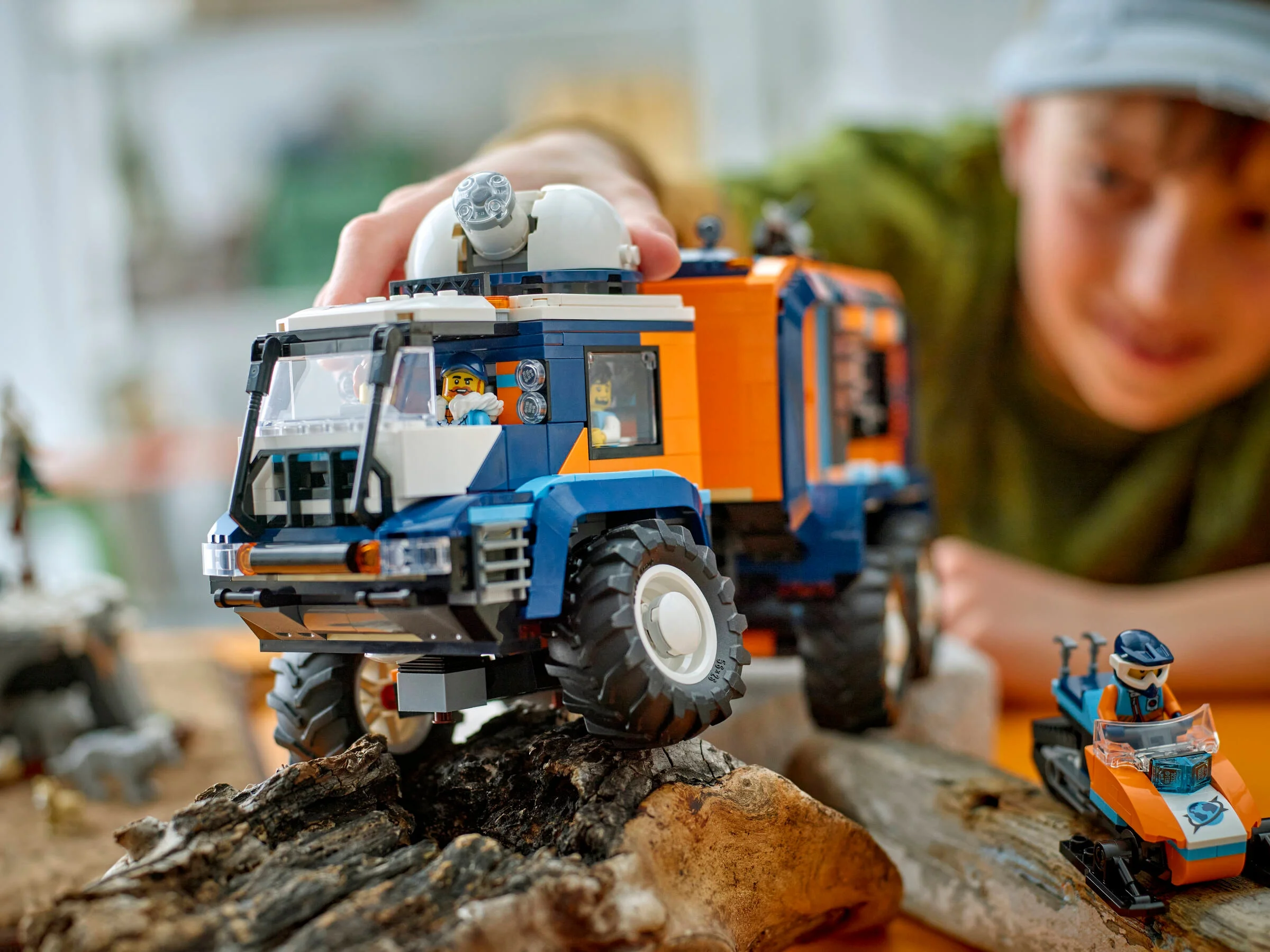 Camionul Arctic LEGO City 60471, albastru și portocaliu, explorat de un copil.