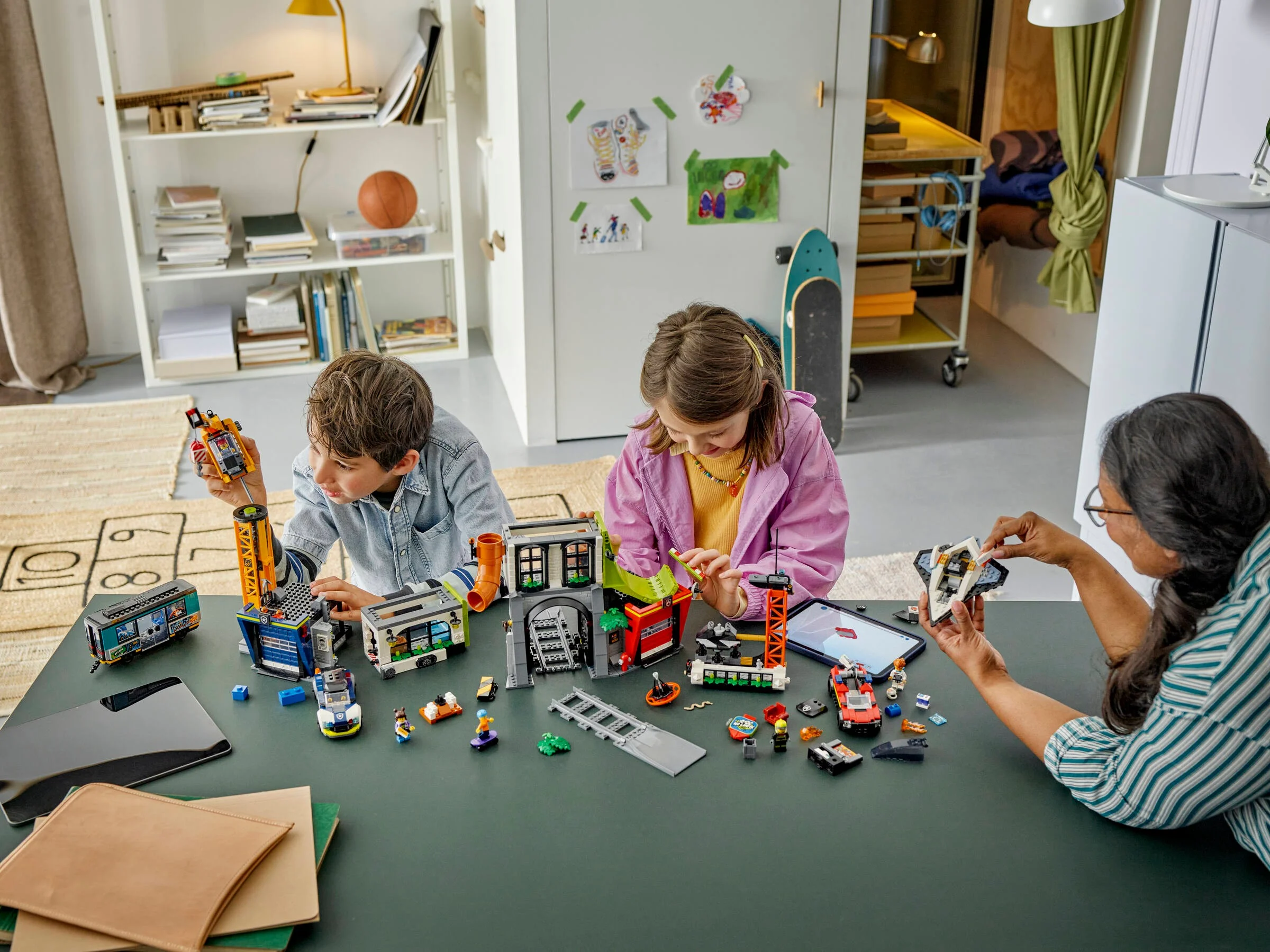 Copii și un adult construiesc setul LEGO City Tower 60473 împreună, zâmbitori și concentrați.