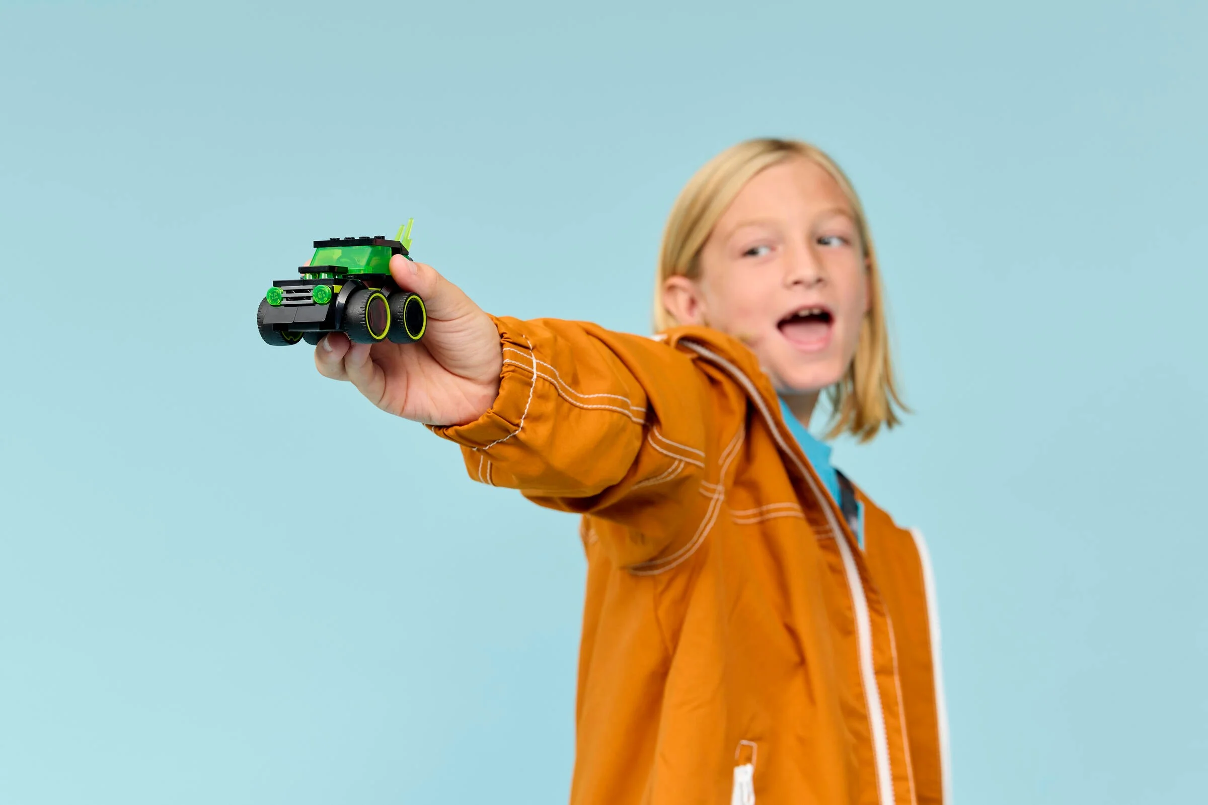 Un copil prezintă mașina de gaming LEGO 60484, zâmbind entuziasmat.