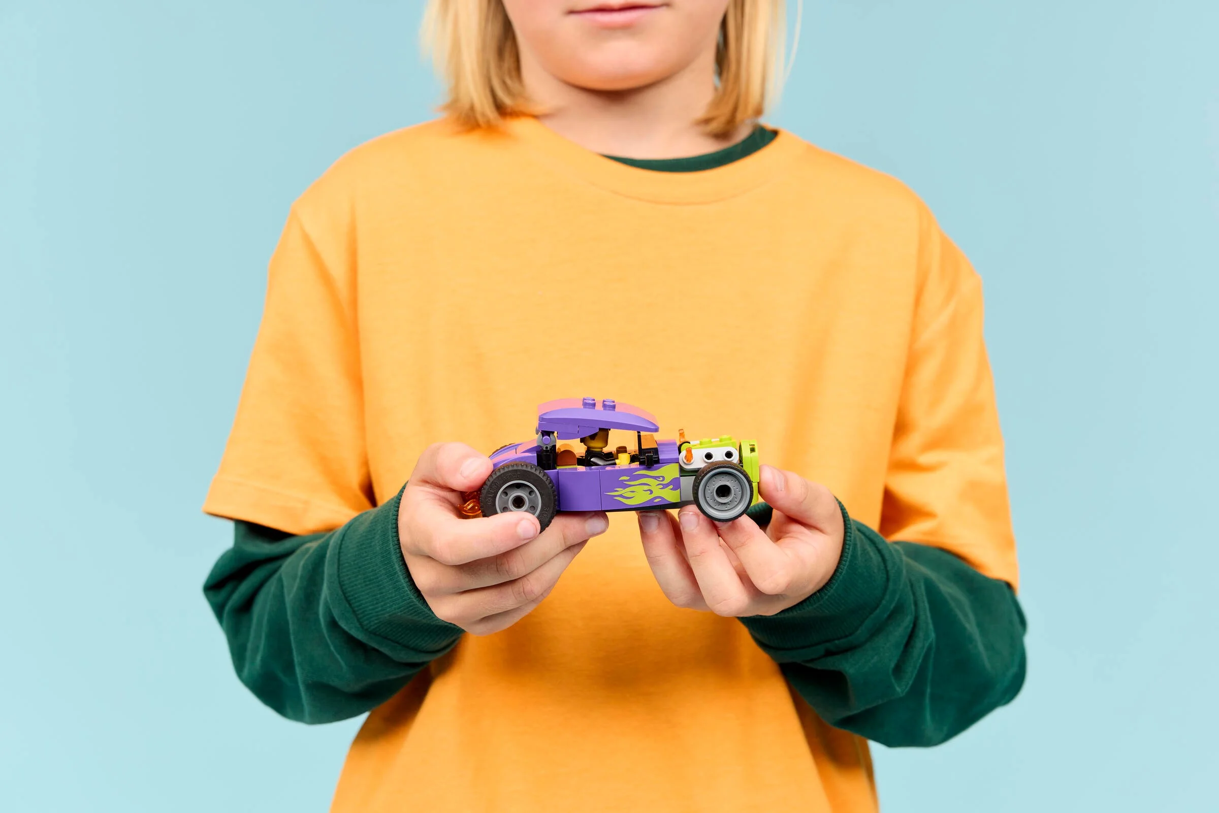 Copil ținând în mâini modelul LEGO Hot Rod, set 60485. Modelul este colorat, viu.