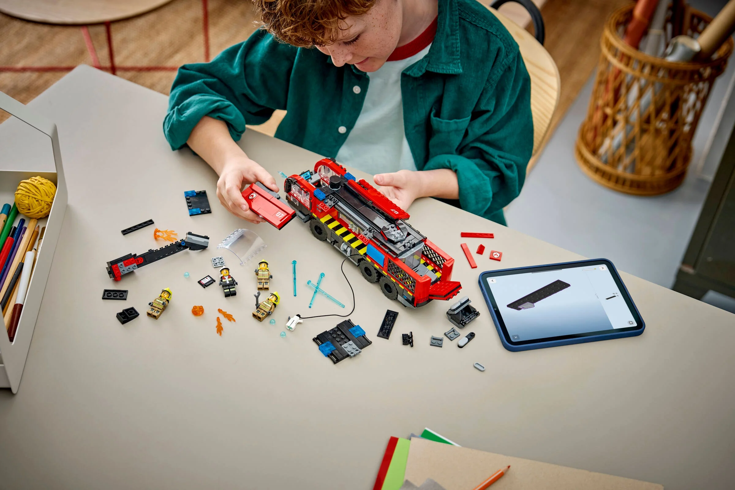 Băiat construind camionul de pompieri LEGO 60499. Instrucțiuni digitale pe tabletă.