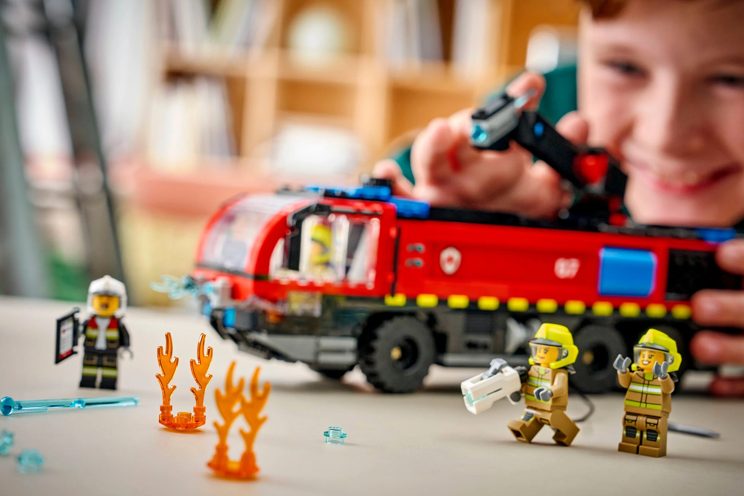 Camion de pompieri cu minifigurine și elemente de flăcări, într-o scenă interactivă.