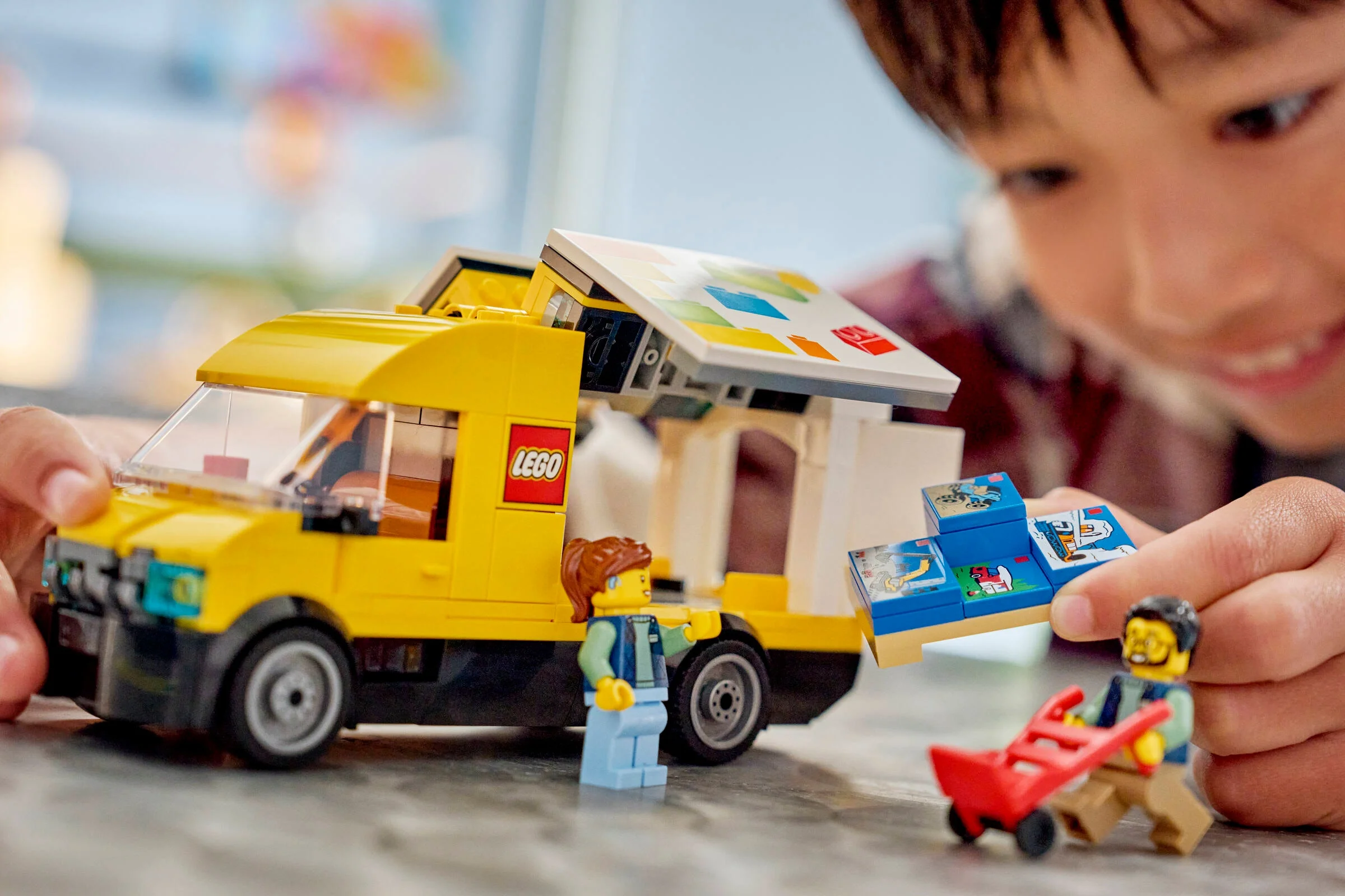 Copil se joacă cu furgoneta LEGO, minifigurine și accesorii.